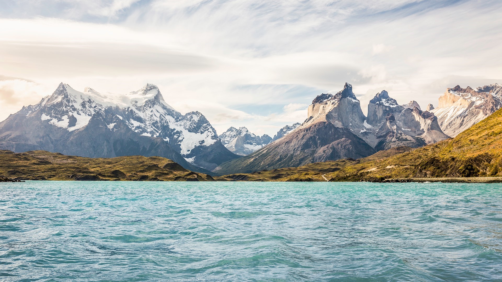 Turquoise lake with snow-capped mountains and rocky shore HD Wallpaper