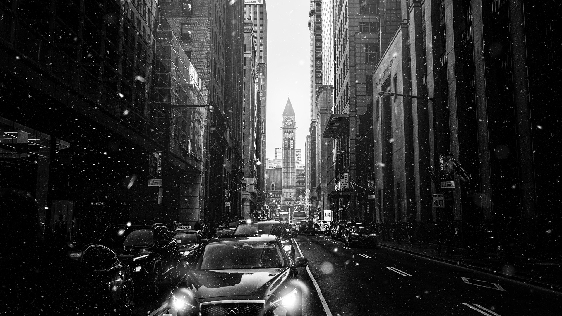 Monochrome cityscape with snow falling on a street with cars and a clock tower. HD Wallpaper