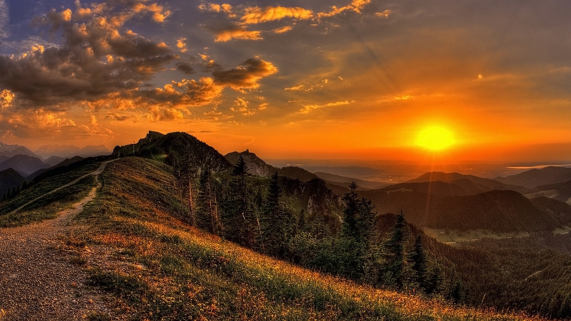 Sunset over a mountain range with a path HD Wallpaper