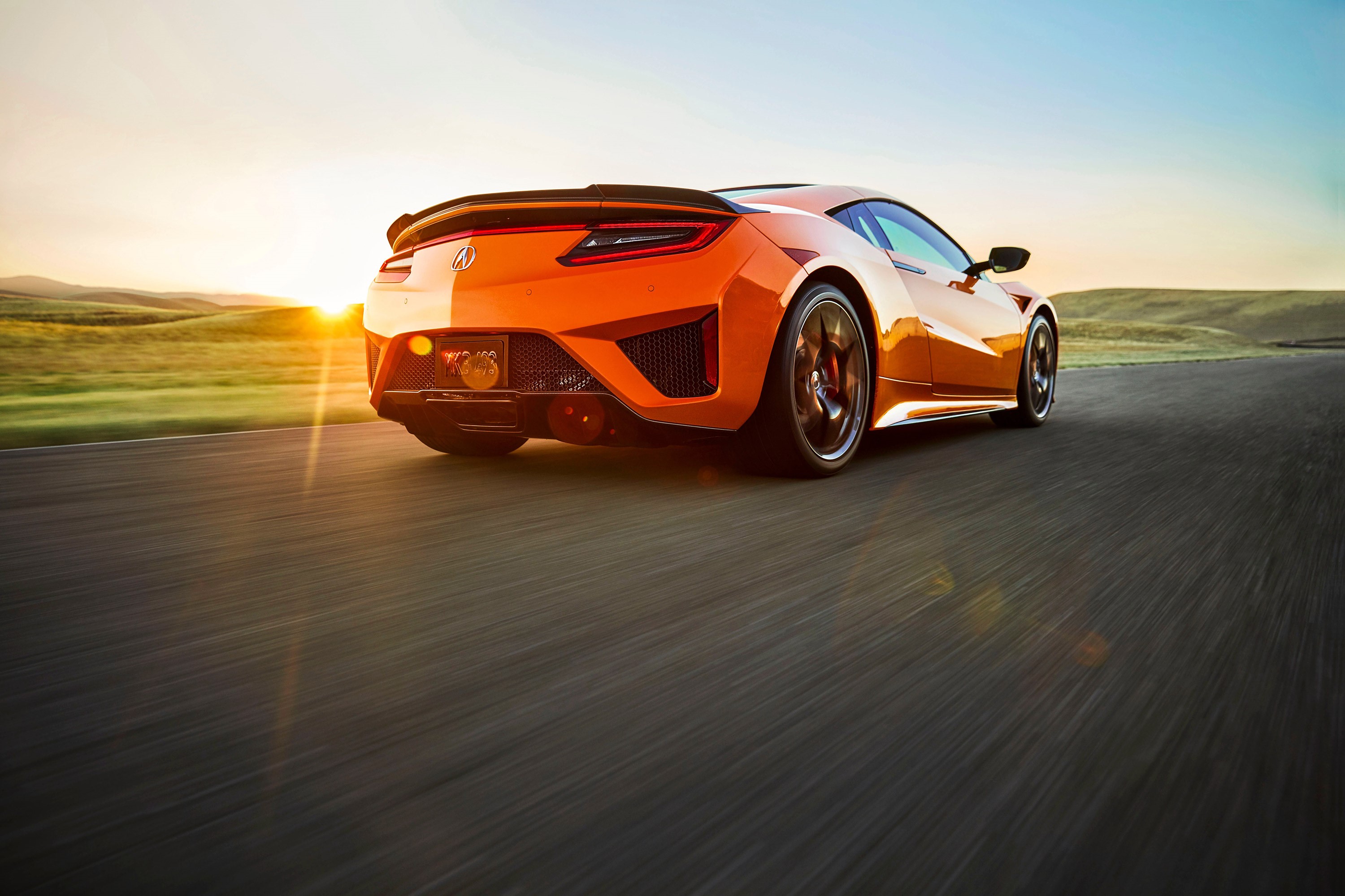 Orange Acura NSX driving on a road at sunset HD Wallpaper