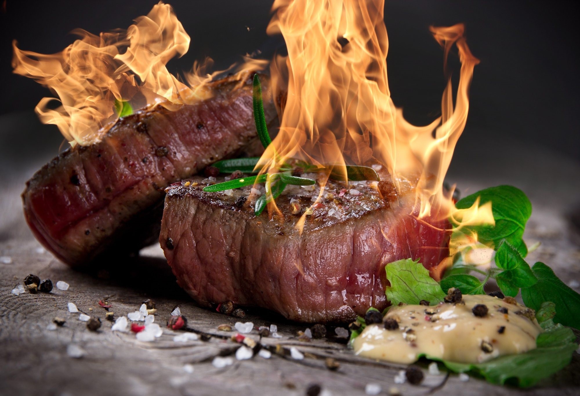 Steak on a wooden surface with flames HD Wallpaper