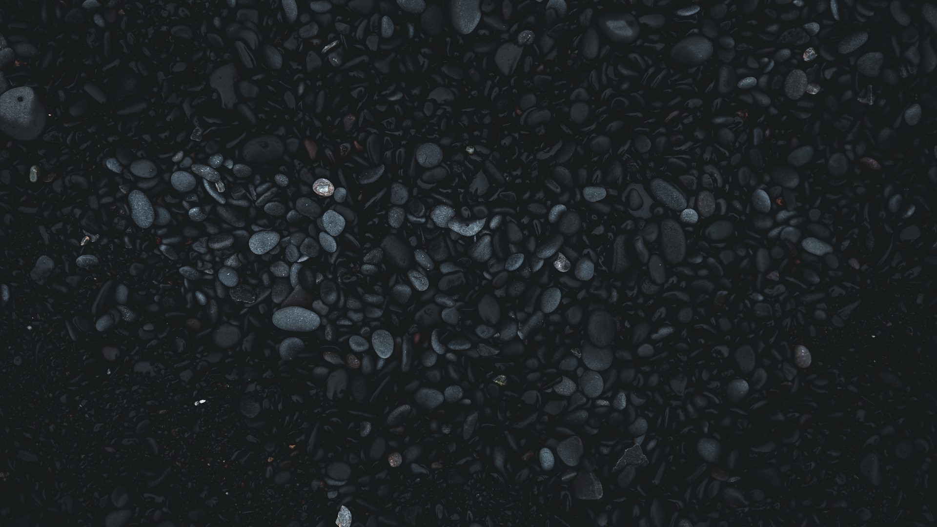 Dark pebbles and sand on a beach HD Wallpaper