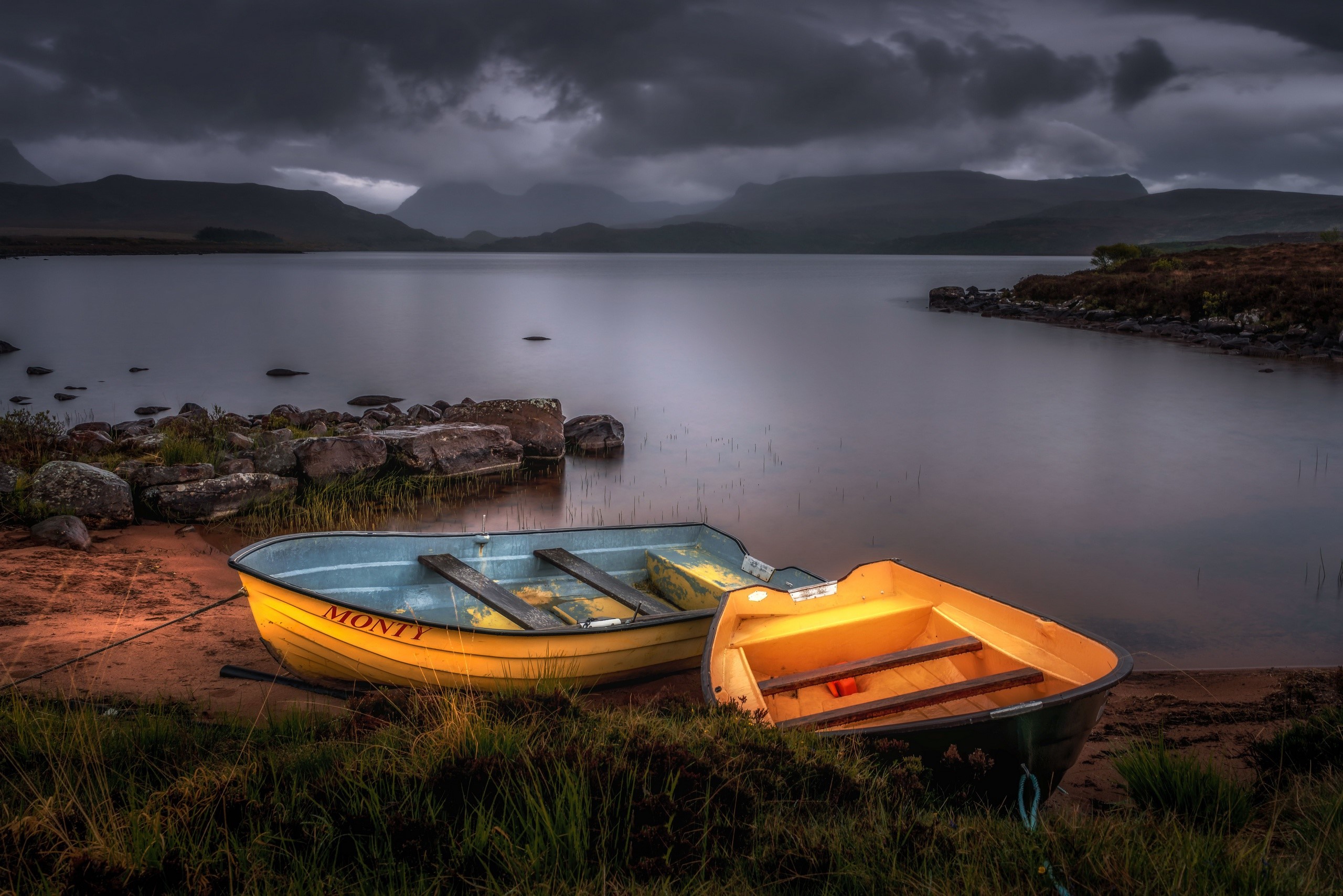 Two boats on a lake shore under stormy skies HD Wallpaper