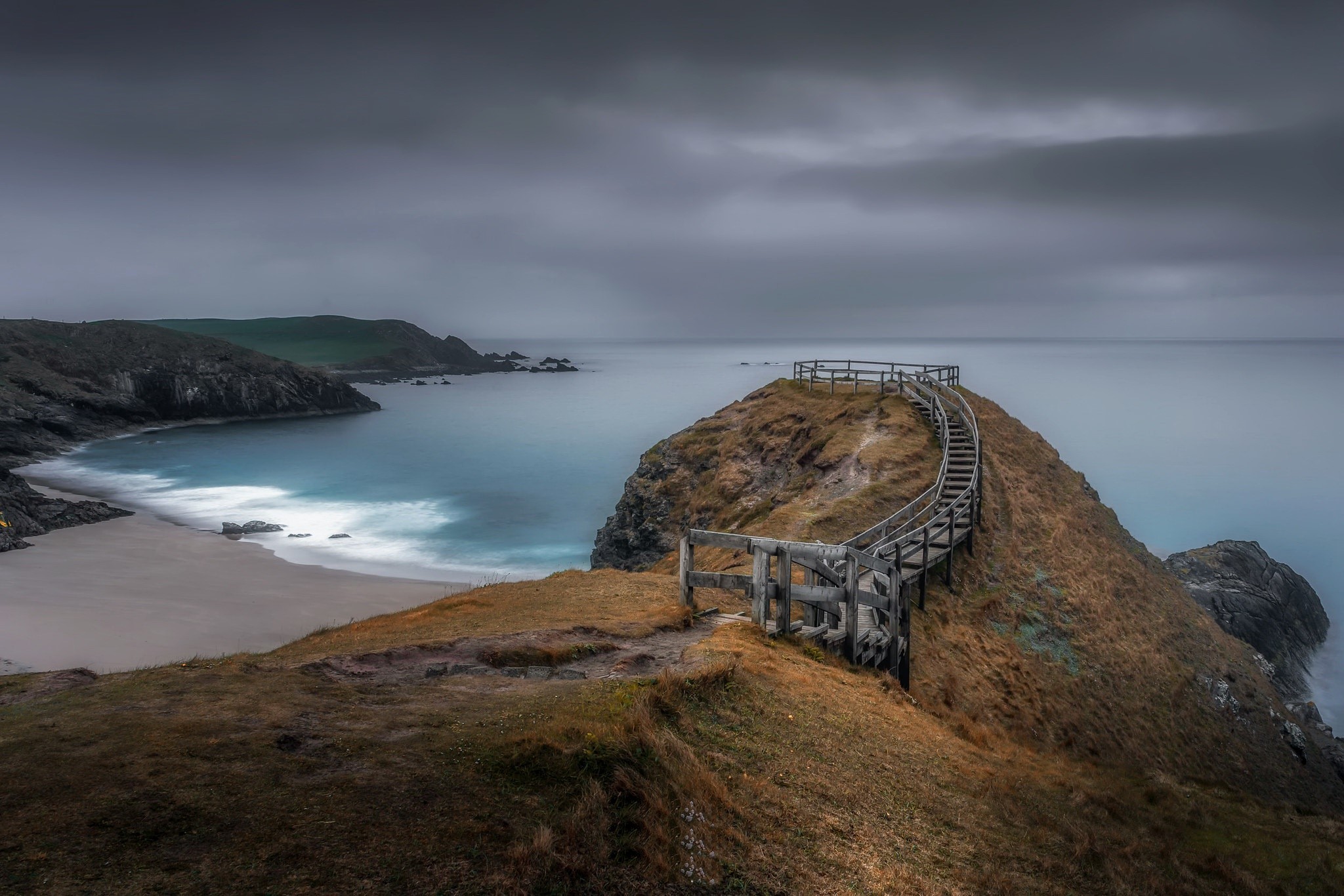 Wooden staircase on a grassy cliff overlooking the sea HD Wallpaper