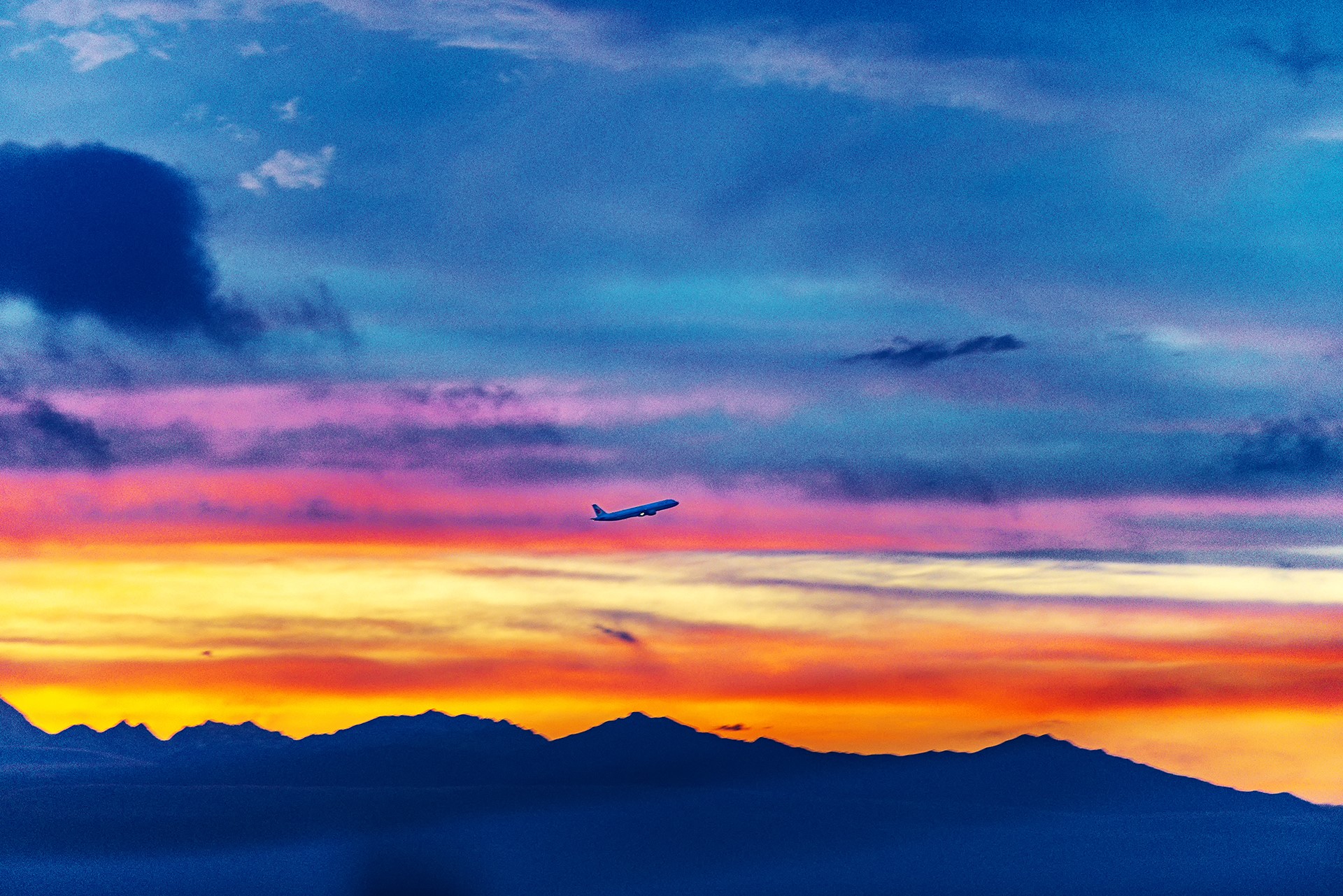 Airplane flying over mountains at sunset HD Wallpaper