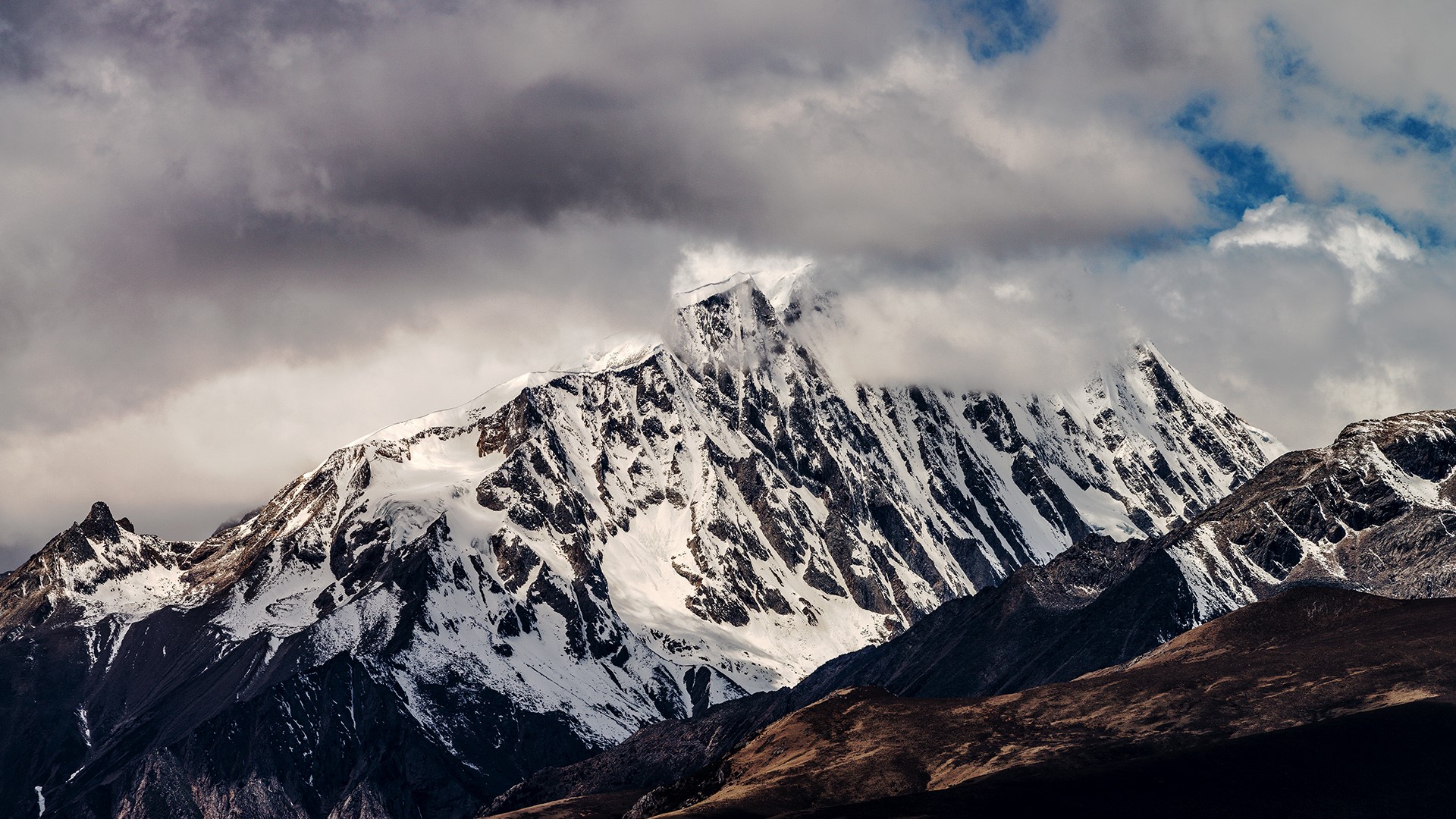 Snow-capped mountains in Sichuan under cloudy skies HD Wallpaper