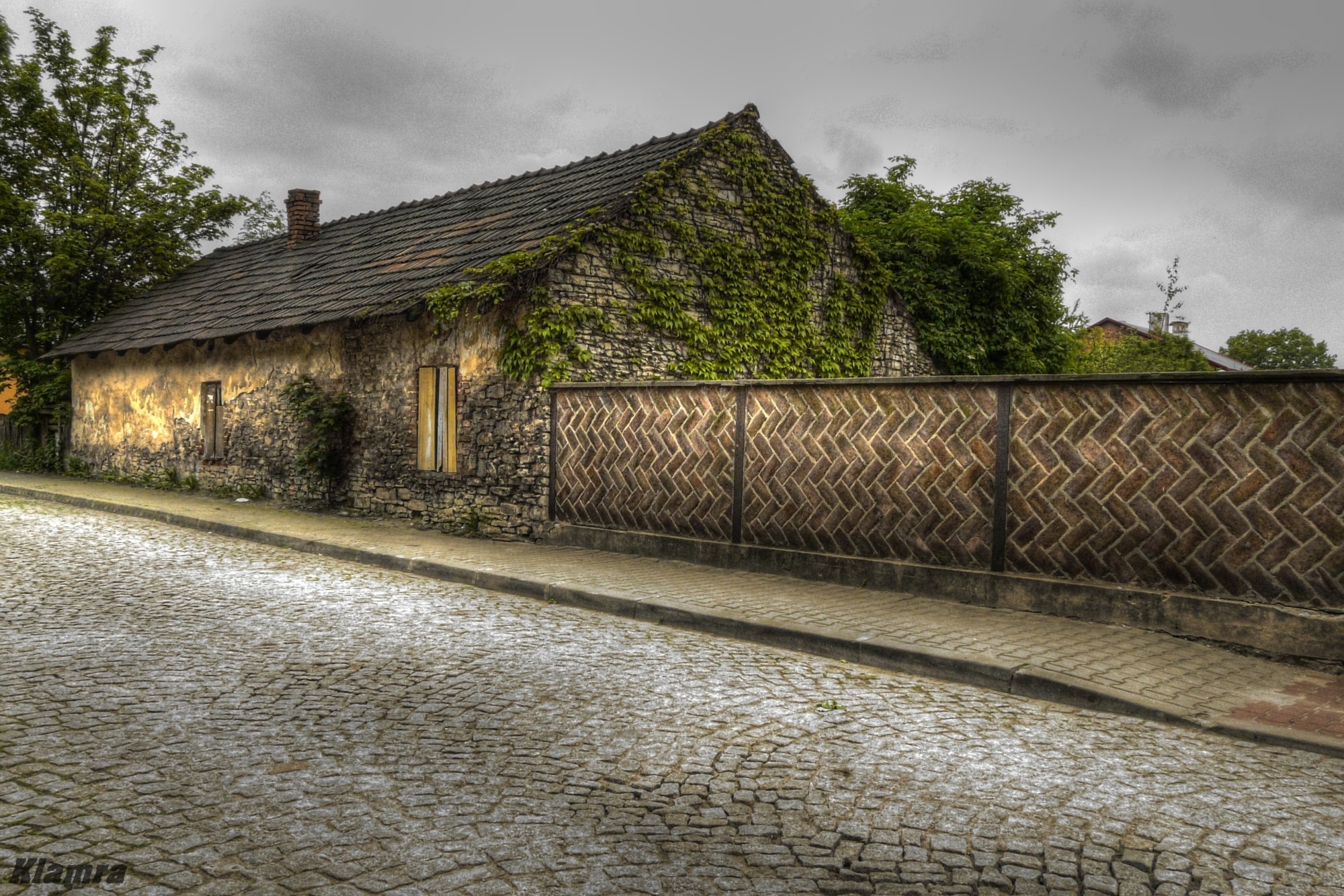 Old stone house covered in ivy with a cobblestone street in Poland HD Wallpaper