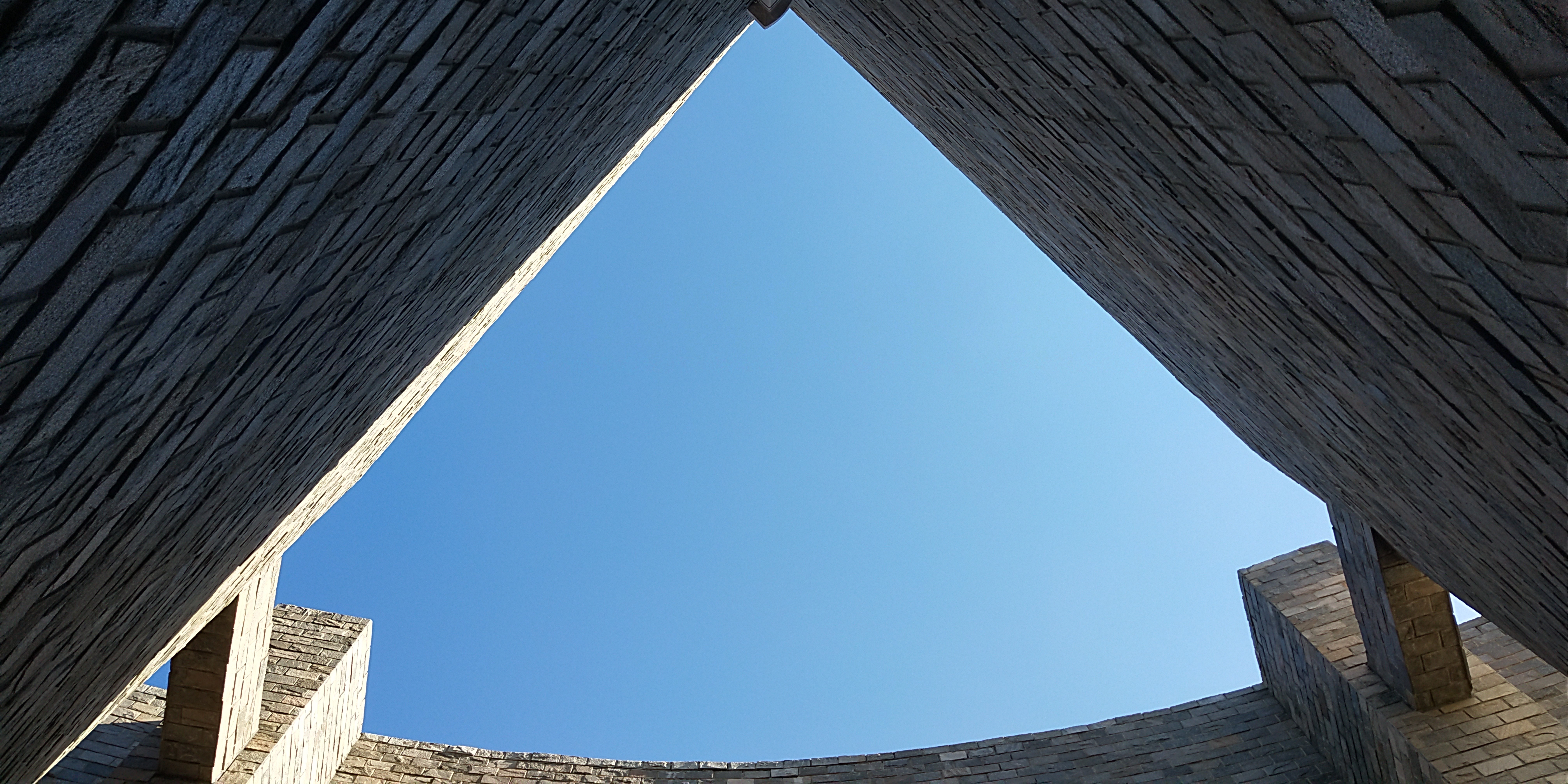 Worm's eye view of brick architecture against blue sky HD Wallpaper
