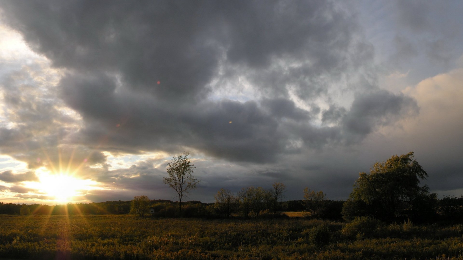 Sunset over a field with dramatic clouds HD Wallpaper
