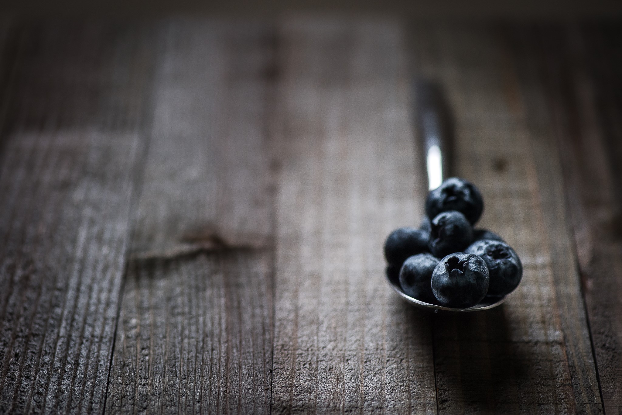 Blueberries on a spoon on a wooden surface HD Wallpaper