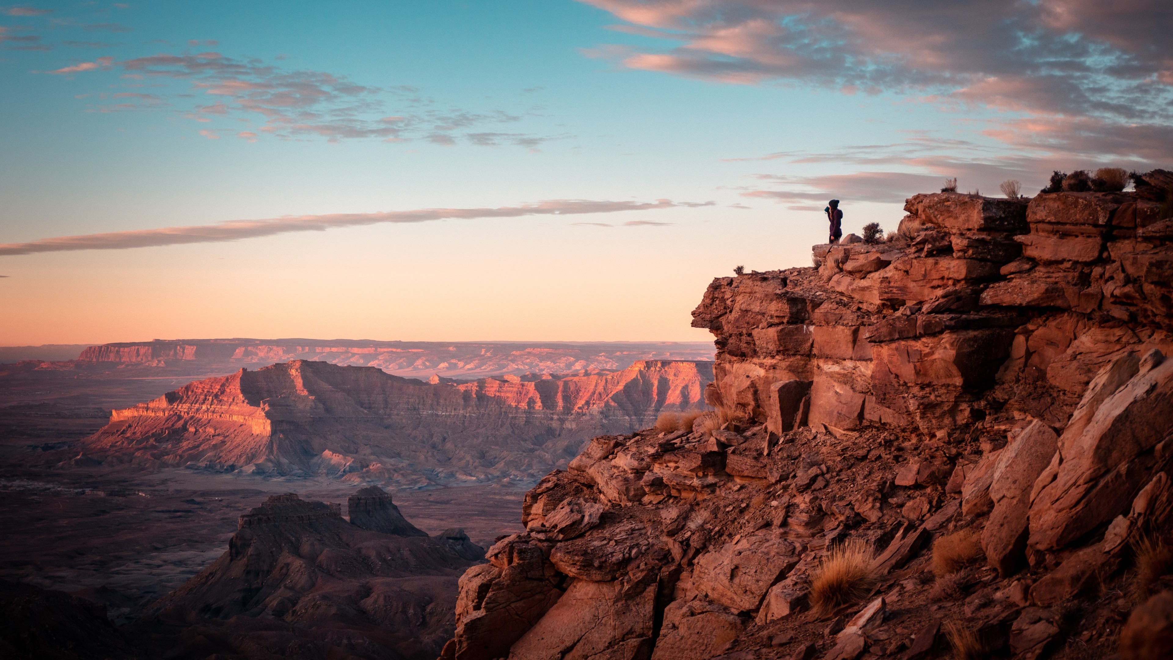 4K sunset over a vast canyon with a person on a cliff HD Wallpaper