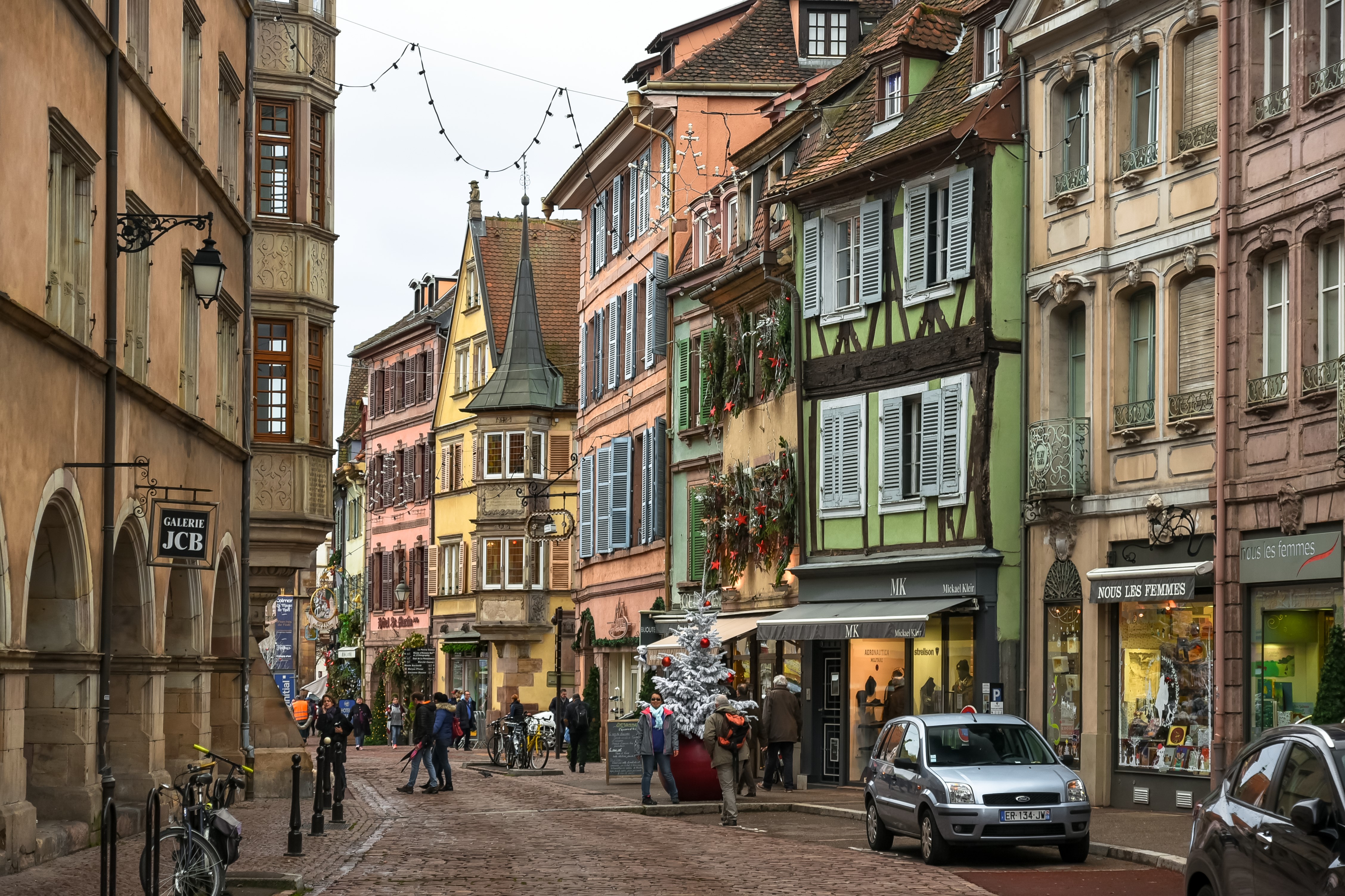 Street scene in Colmar, France with people and shops HD Wallpaper