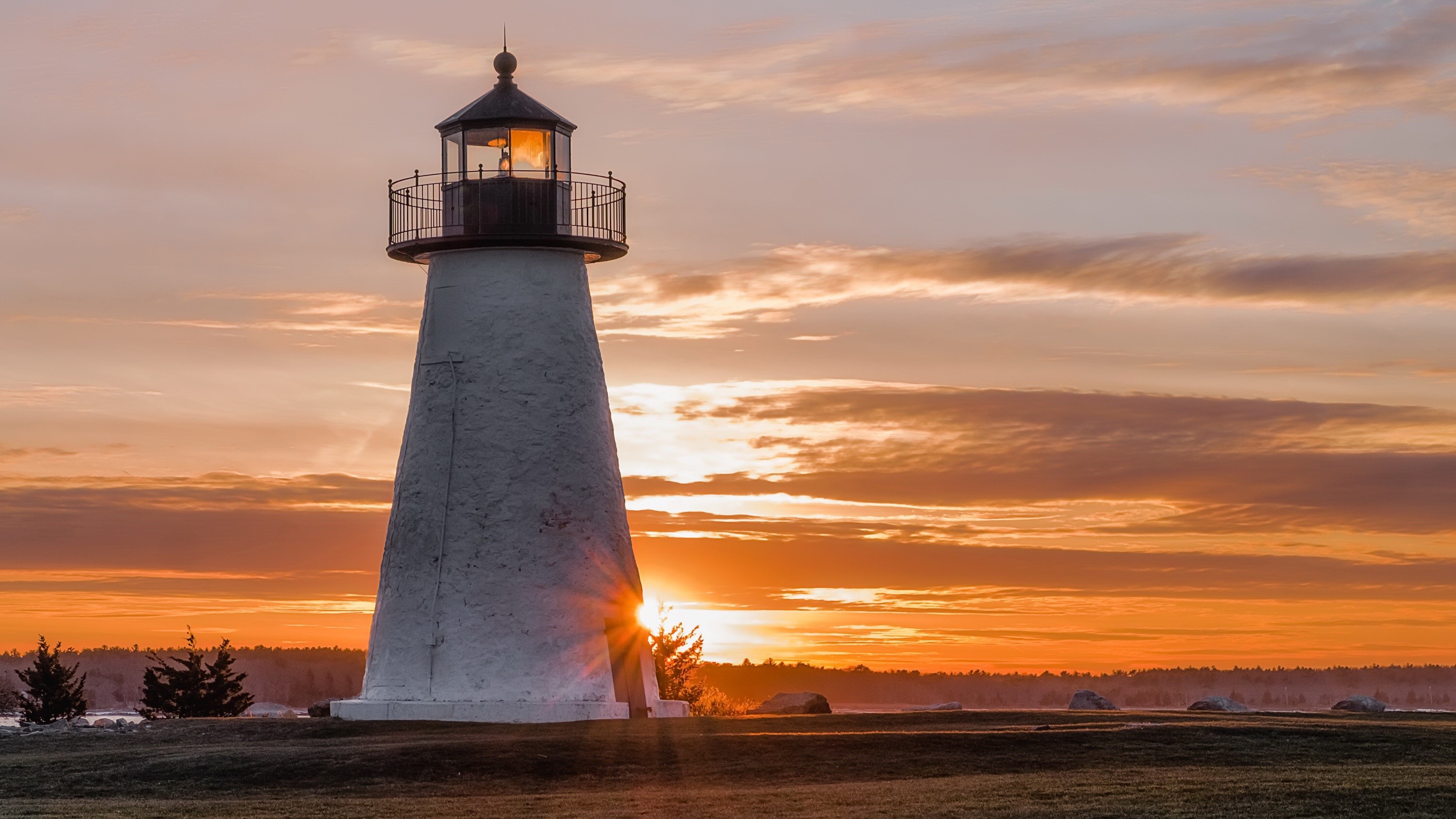 White lighthouse at sunset with orange sky HD Wallpaper