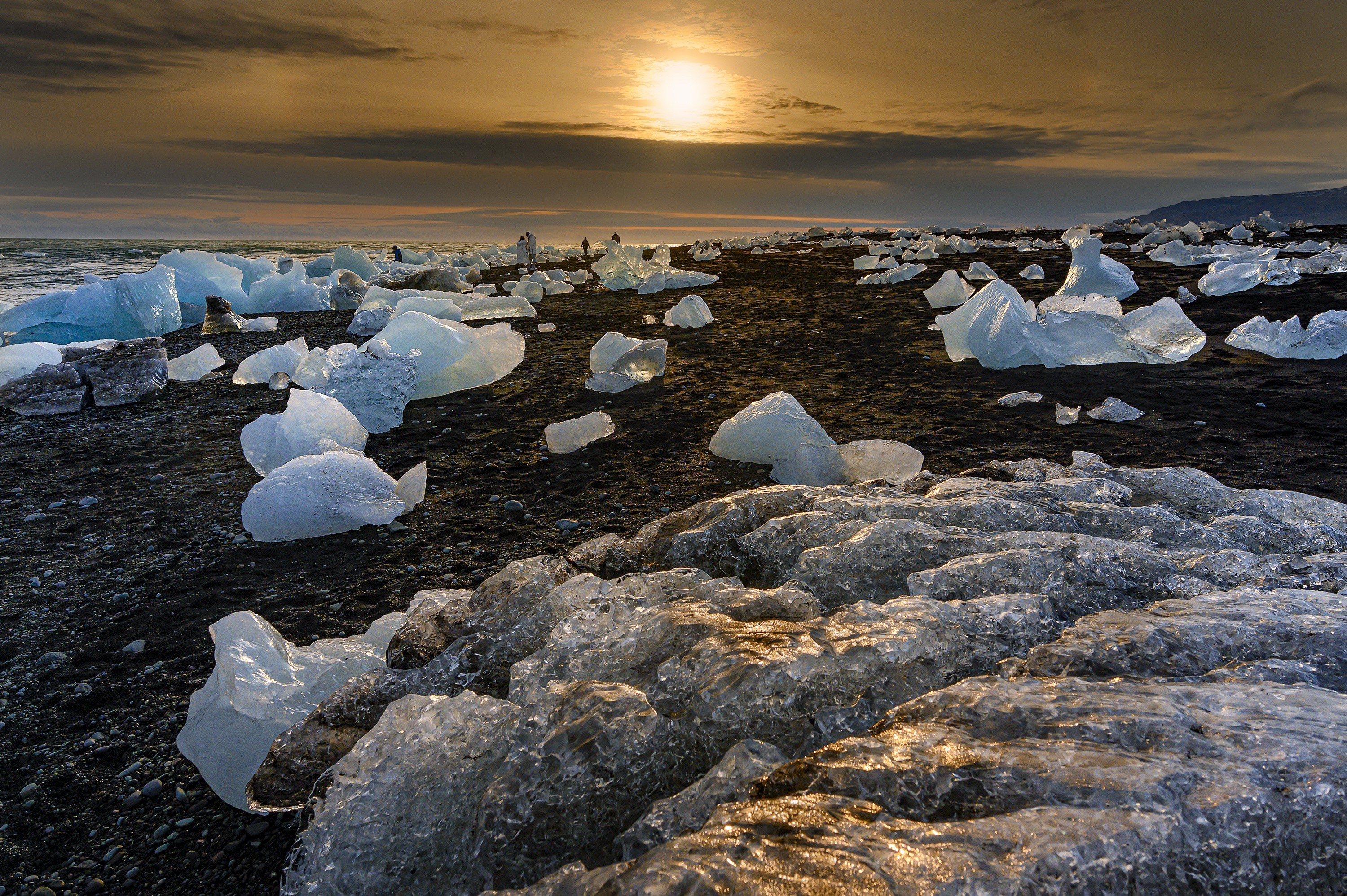 Icebergs on a black sand beach at sunset HD Wallpaper