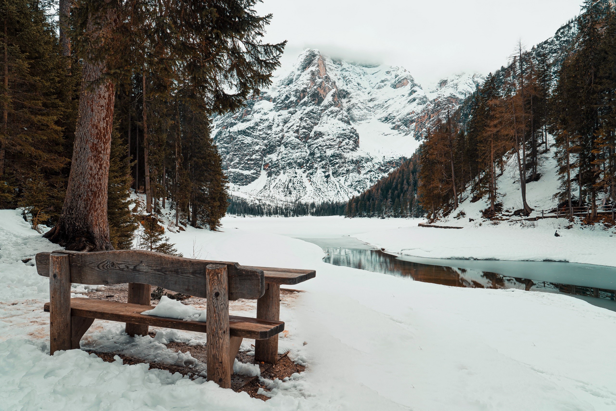 Wooden bench in front of a snowy mountain landscape HD Wallpaper