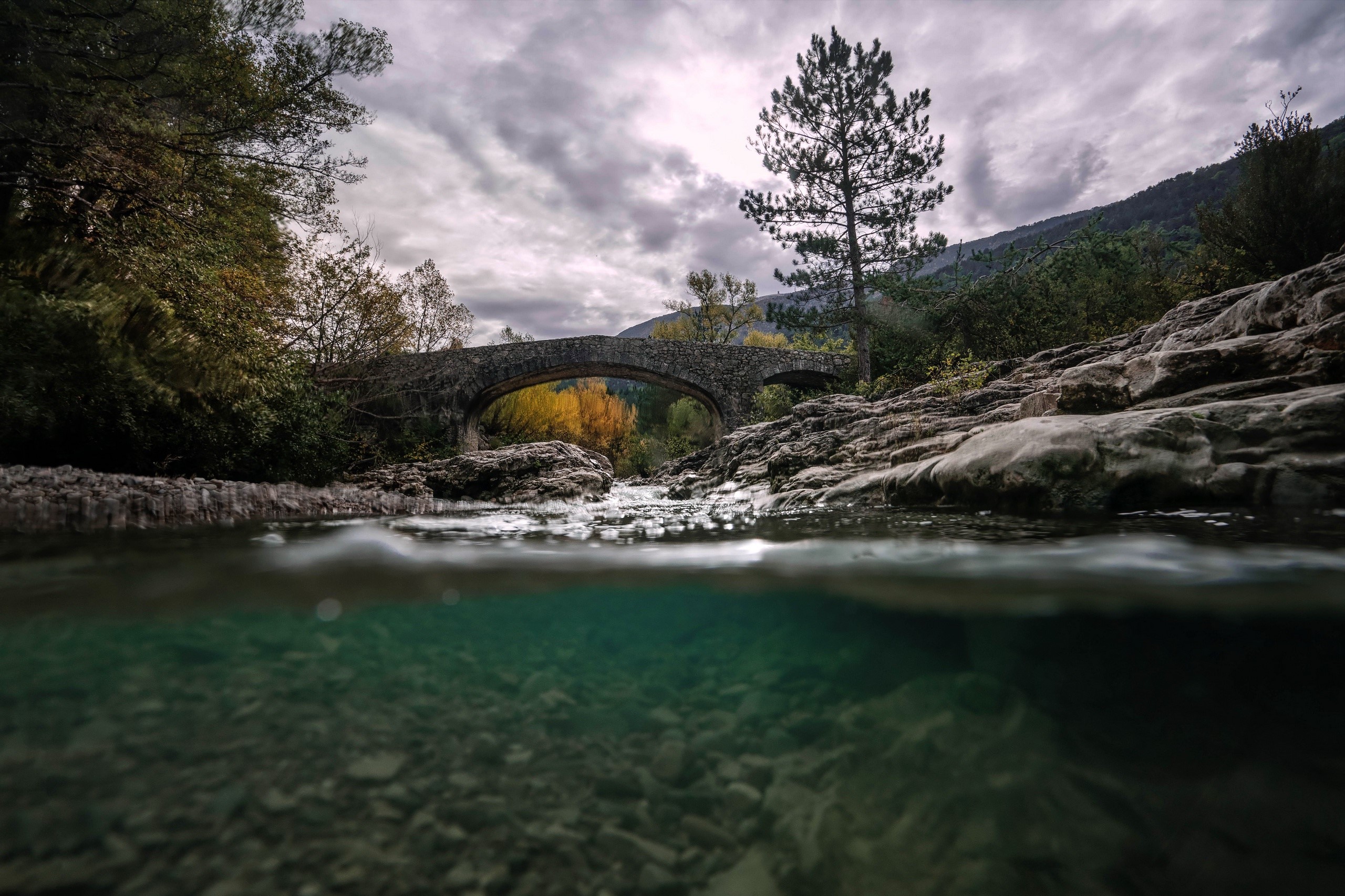 Stone bridge over a river in a forest HD Wallpaper