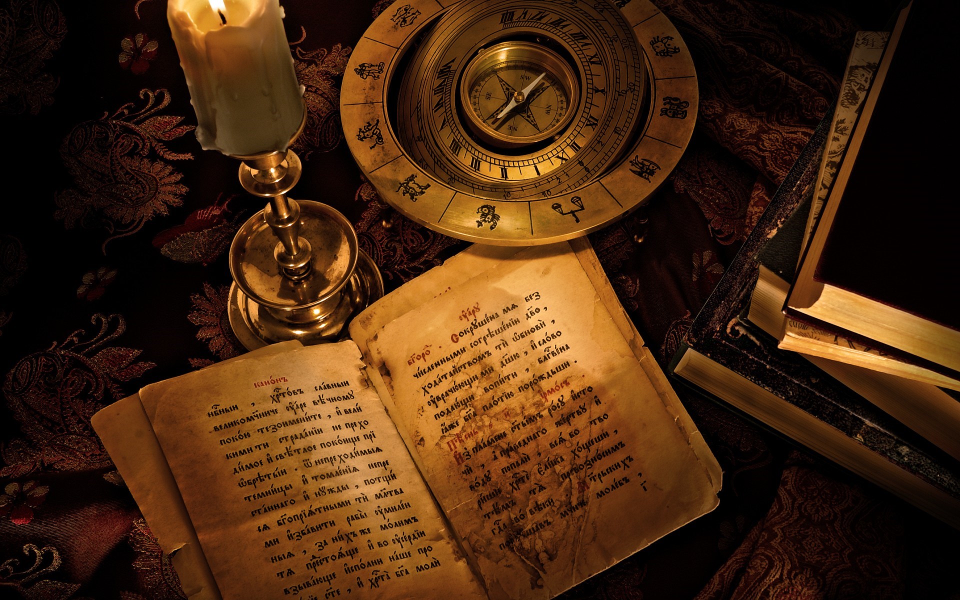 Candle, compass, and old books on a patterned cloth HD Wallpaper