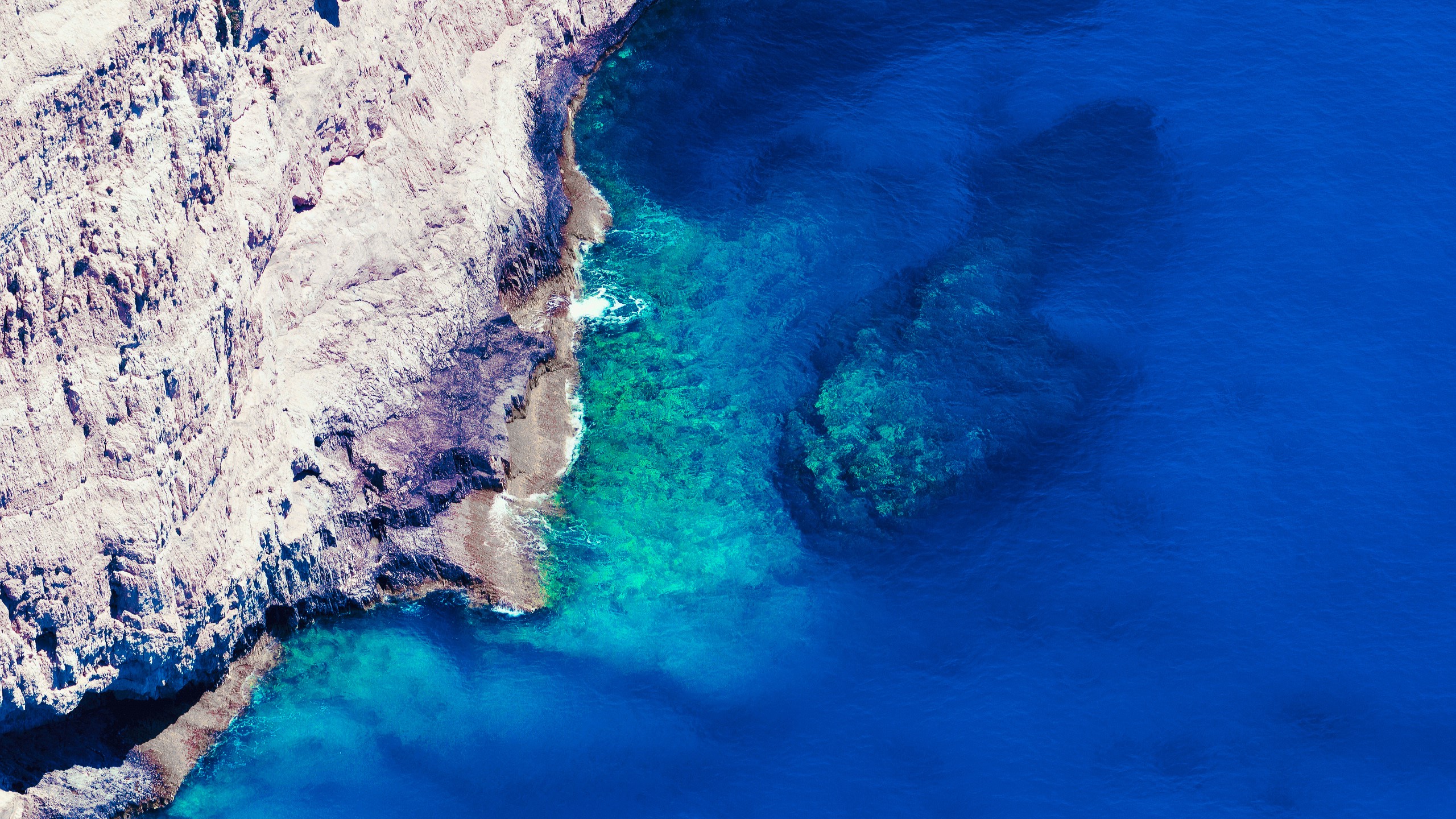 Aerial view of rocky coastline and clear blue ocean HD Wallpaper