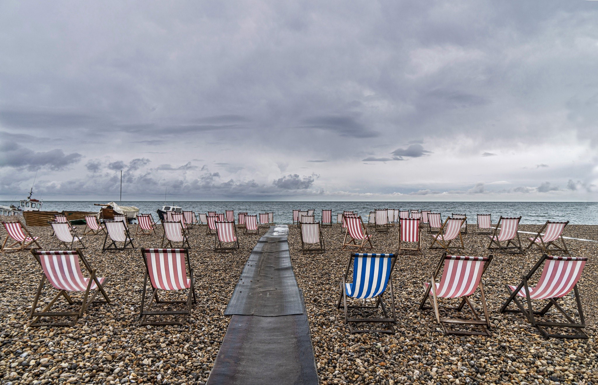 Deck chairs on a pebble beach in England HD Wallpaper