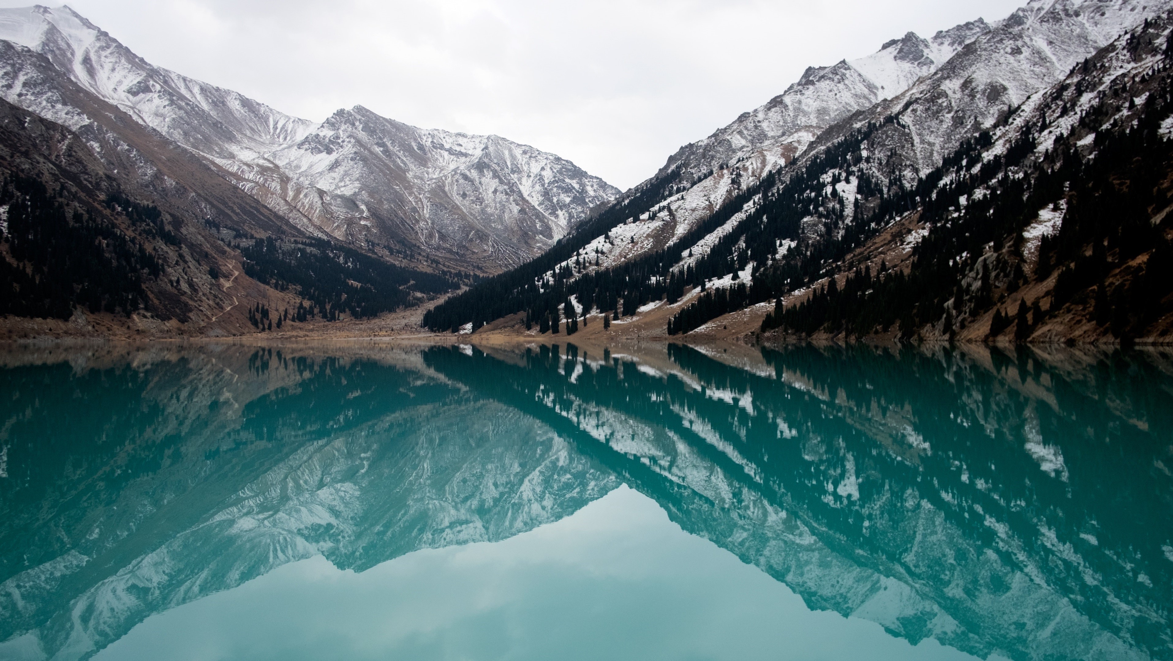 Snow-capped mountains reflected in a turquoise lake HD Wallpaper