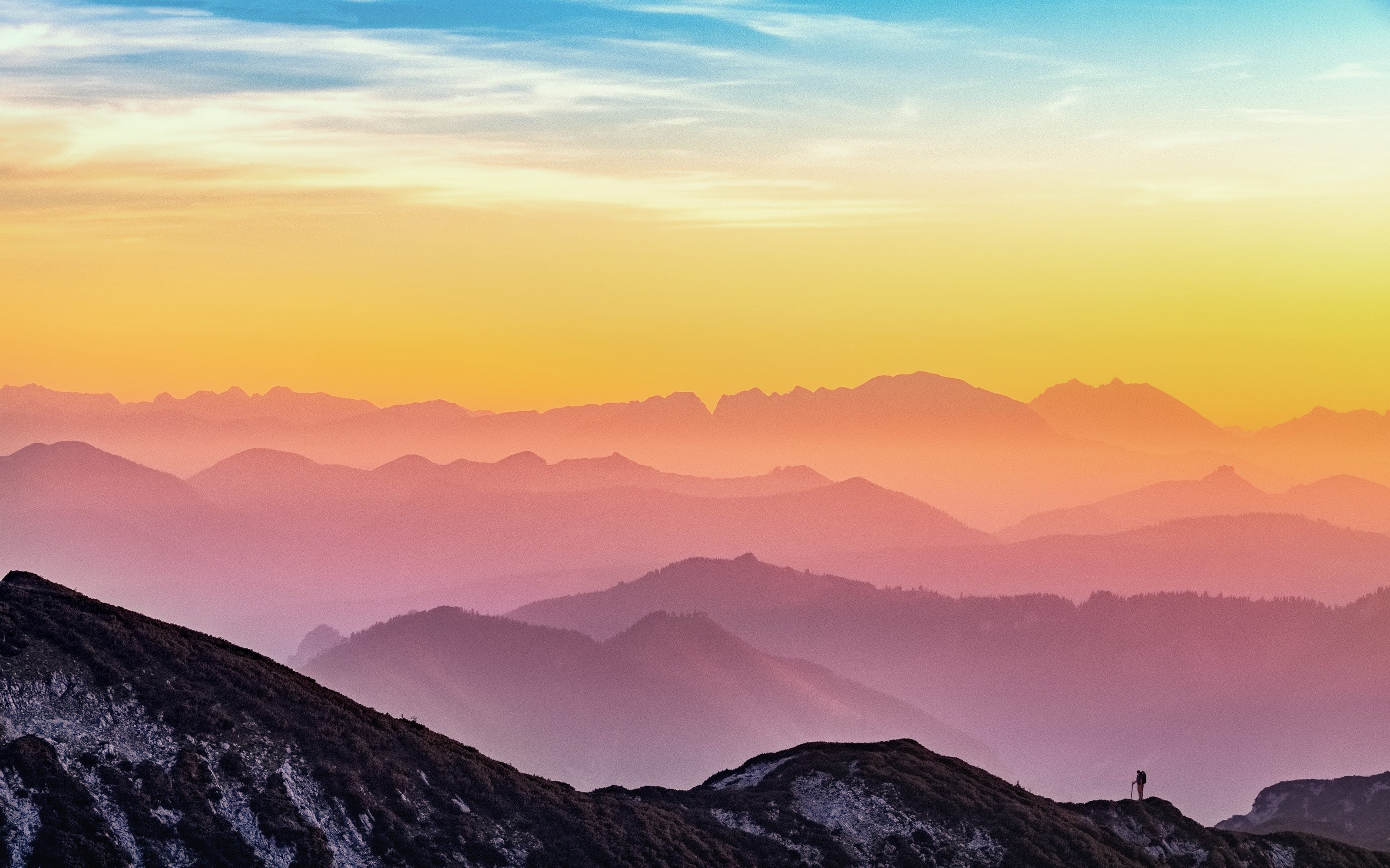 Mountain range at sunset with a lone hiker HD Wallpaper