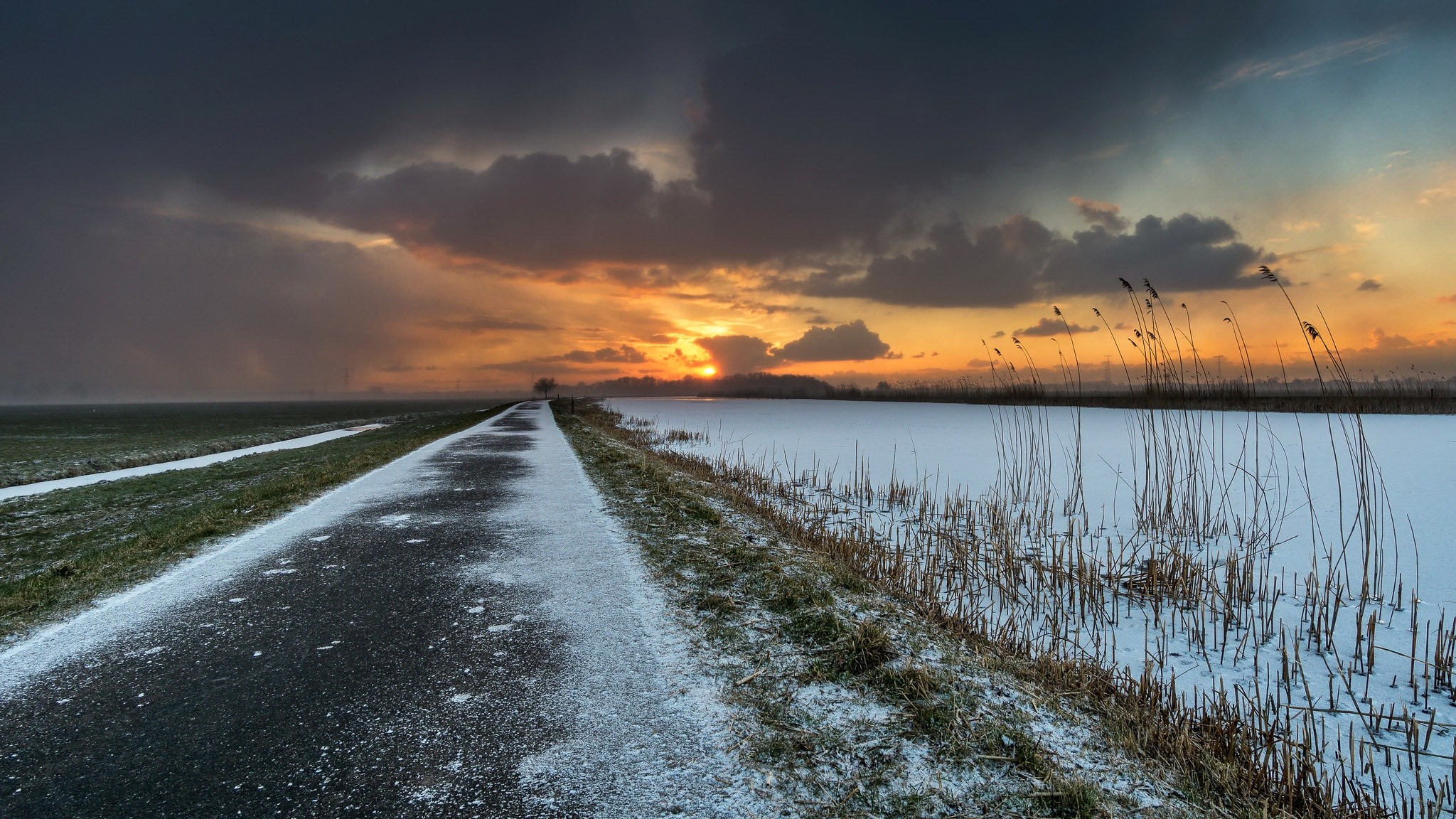Winter sunset over a frozen landscape with a road HD Wallpaper