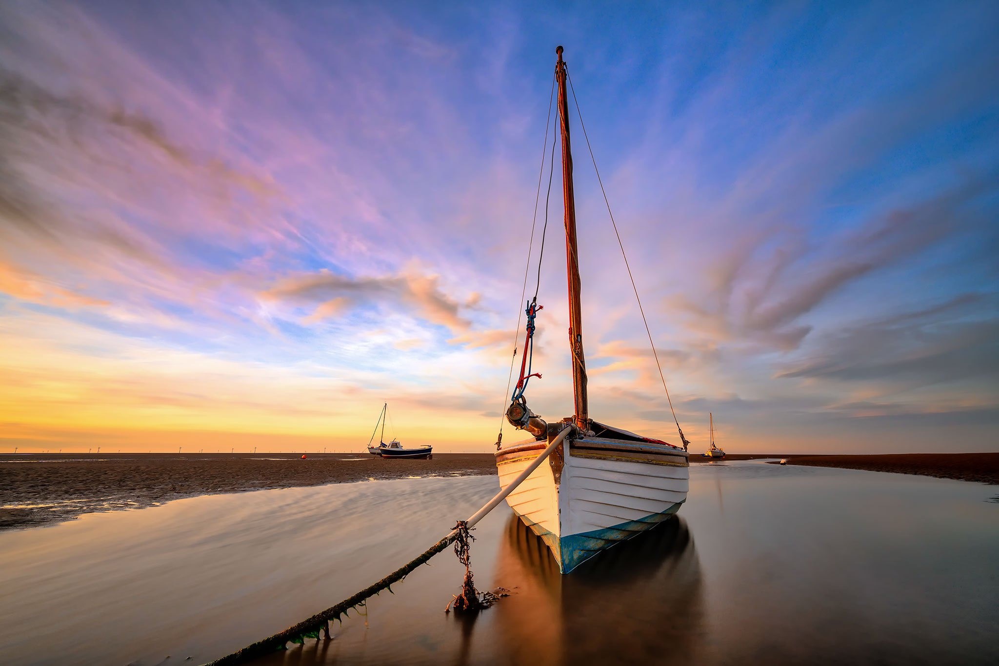 Sailboat moored on a sandy beach at sunset HD Wallpaper