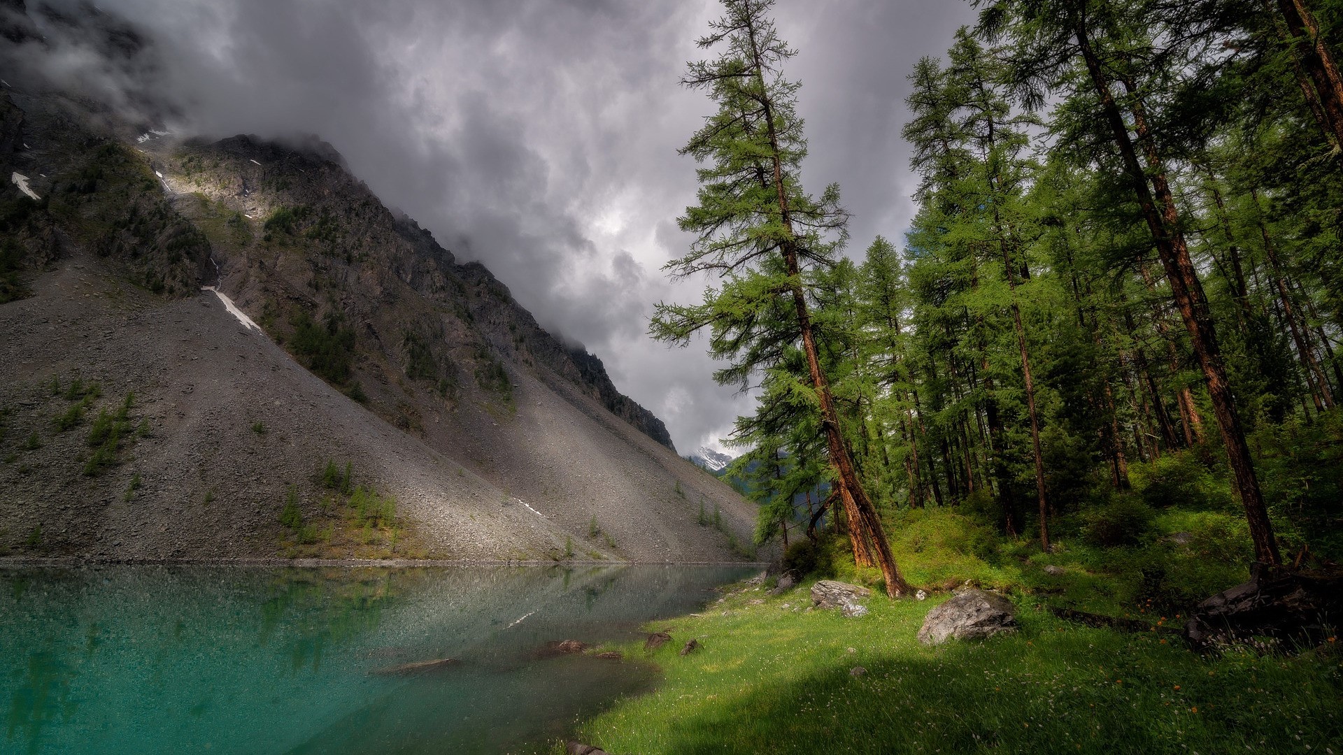 Turquoise lake at the foot of a rocky mountain with a forest HD Wallpaper