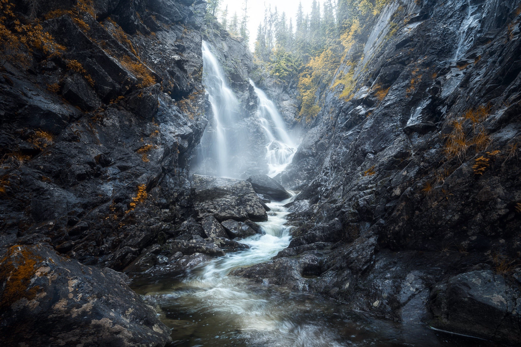 Waterfall cascading down rocky gorge with trees HD Wallpaper