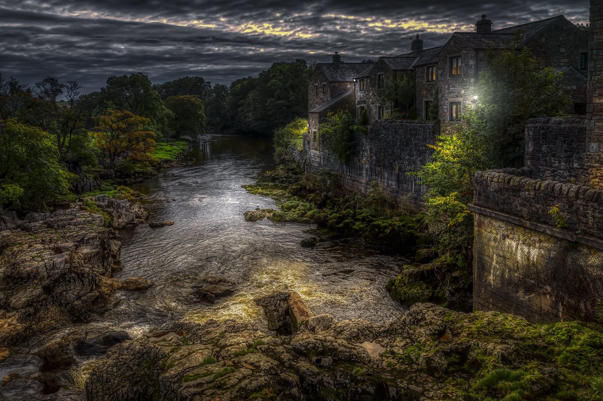 River flowing past stone buildings at night HD Wallpaper