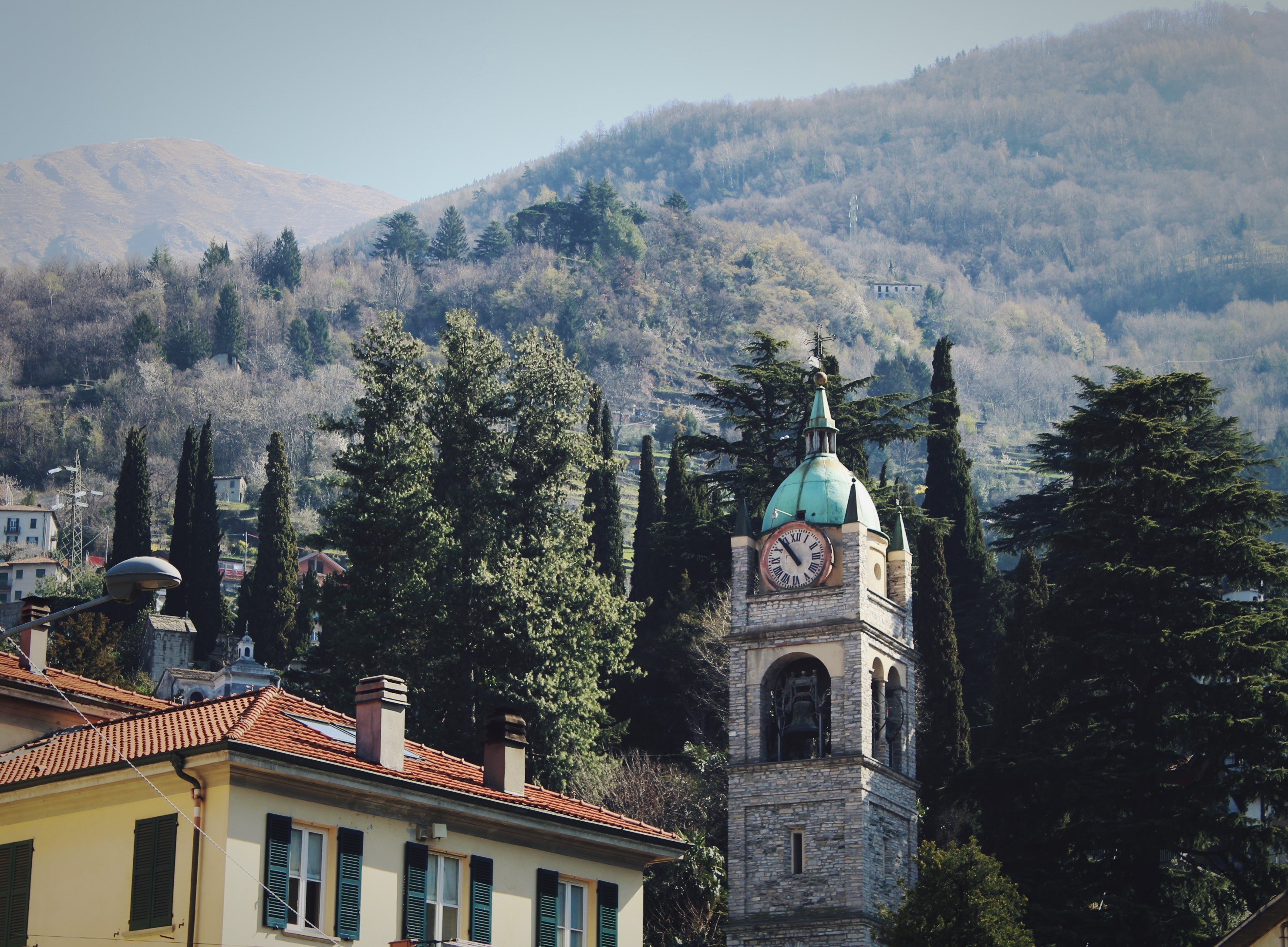 Bell tower in a village with mountains in the background HD Wallpaper