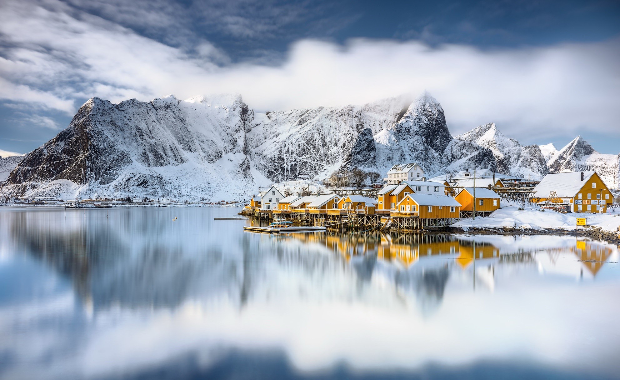 Snowy mountains and yellow houses reflected in water HD Wallpaper