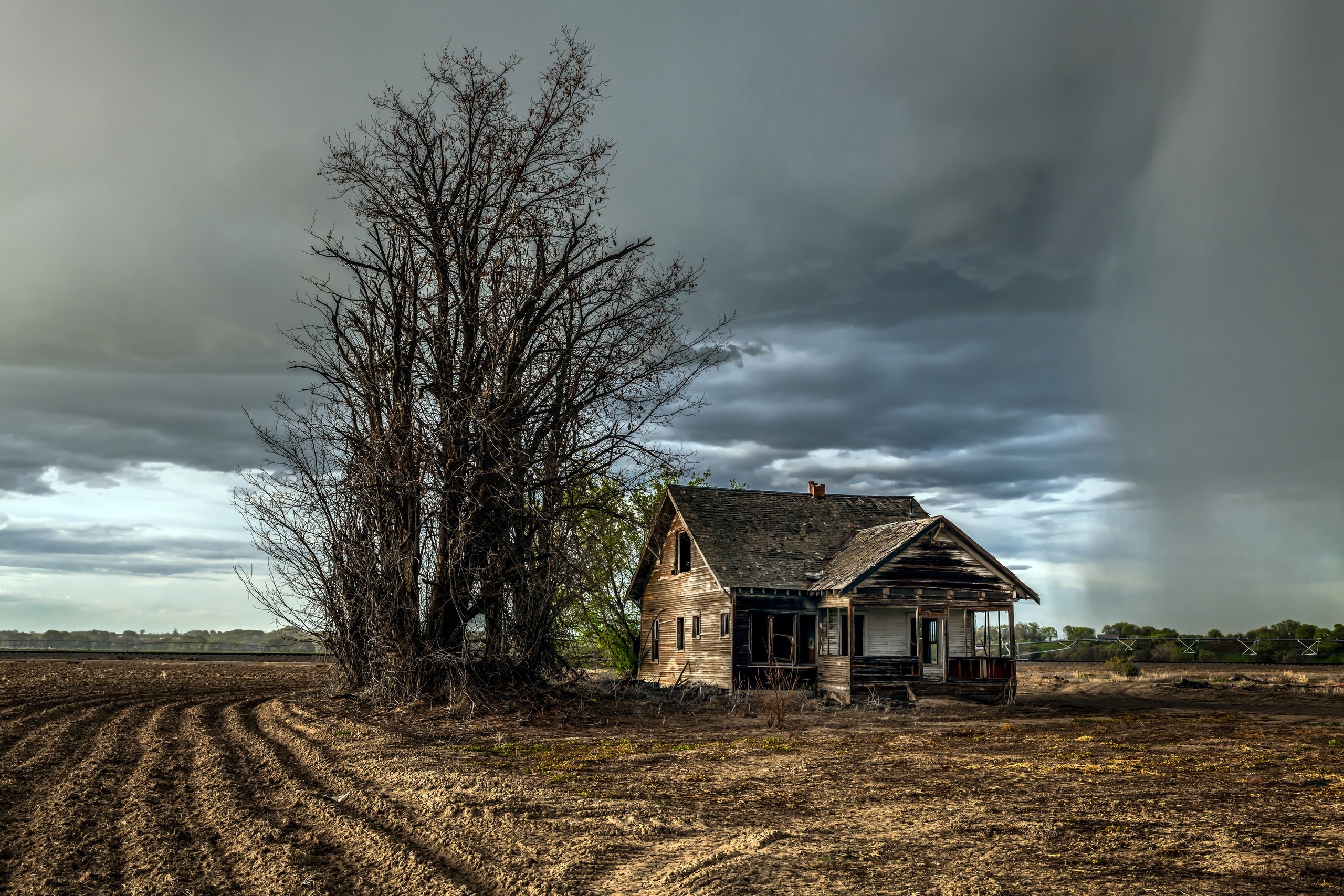 Abandoned house in a field under stormy skies HD Wallpaper