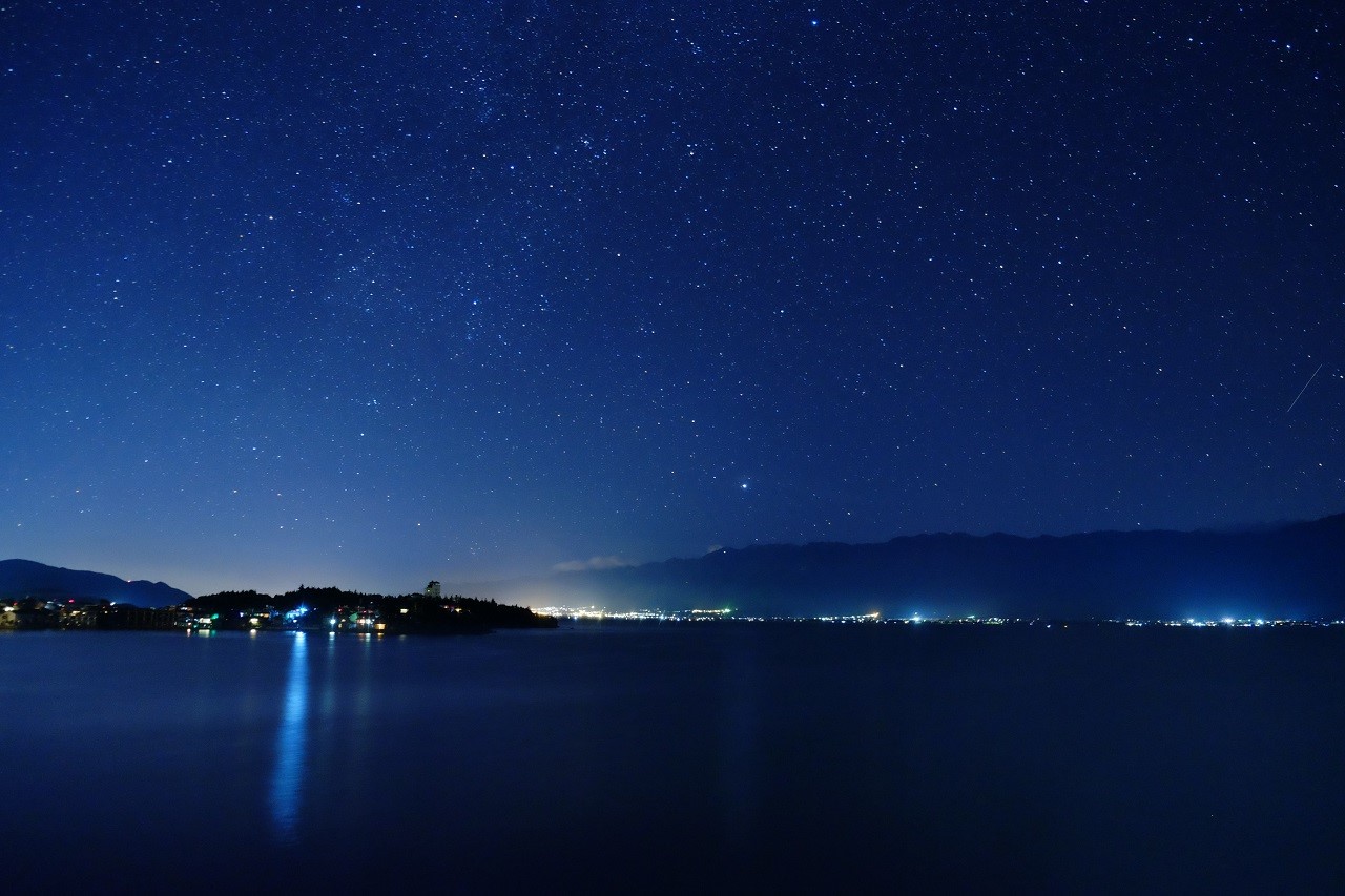 Night sky over a lake with city lights HD Wallpaper