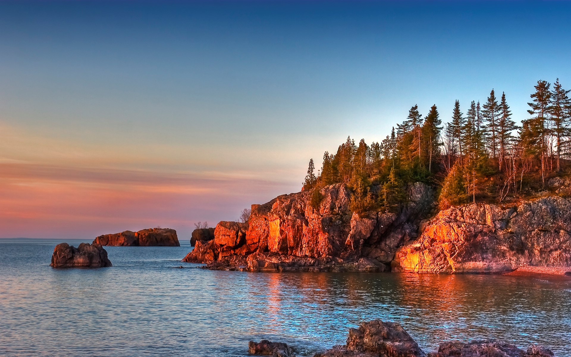 Rocky shoreline with trees at sunset HD Wallpaper