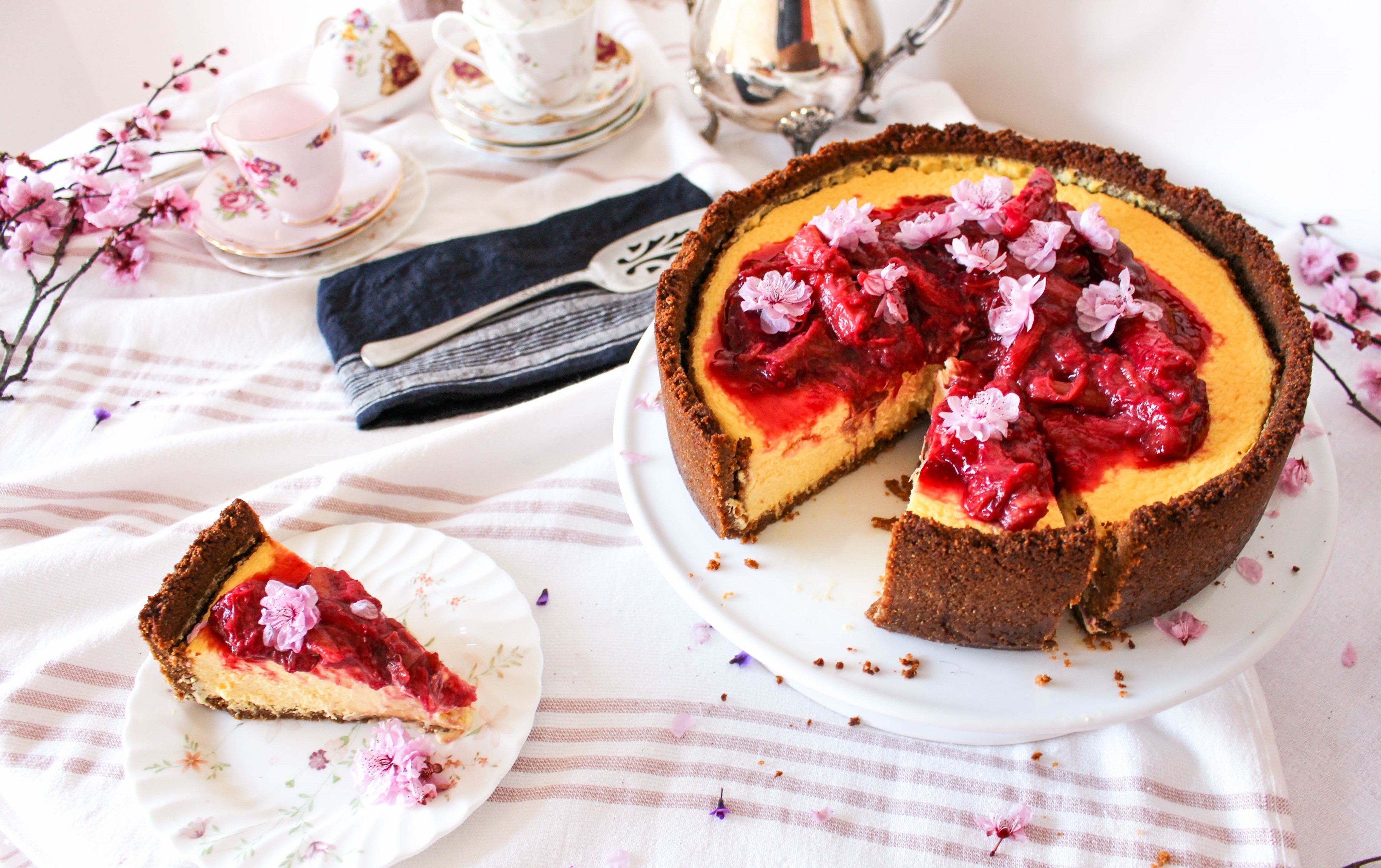 Cheesecake with strawberry topping and pink flowers HD Wallpaper