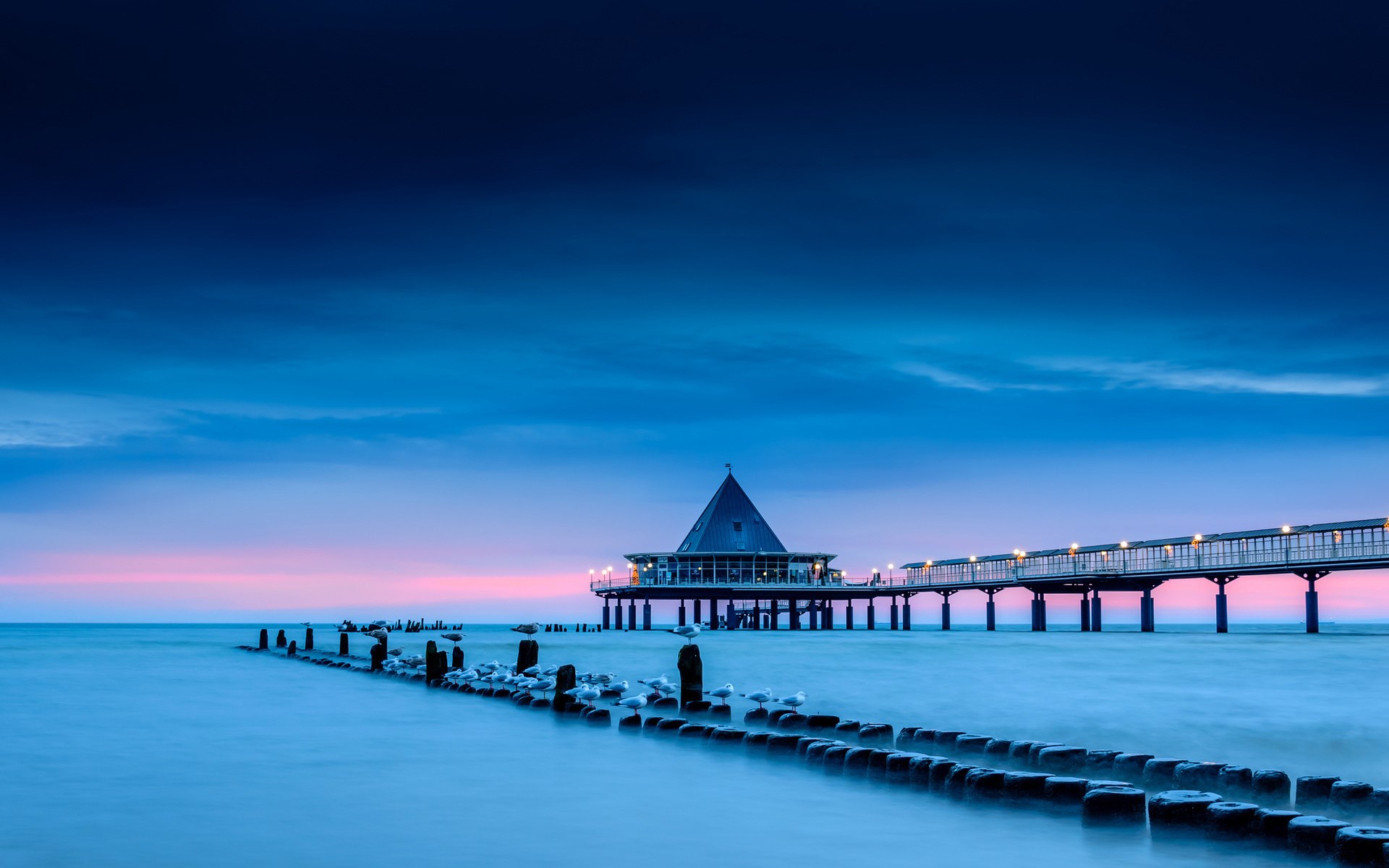 Pier with a building at dusk over the sea HD Wallpaper