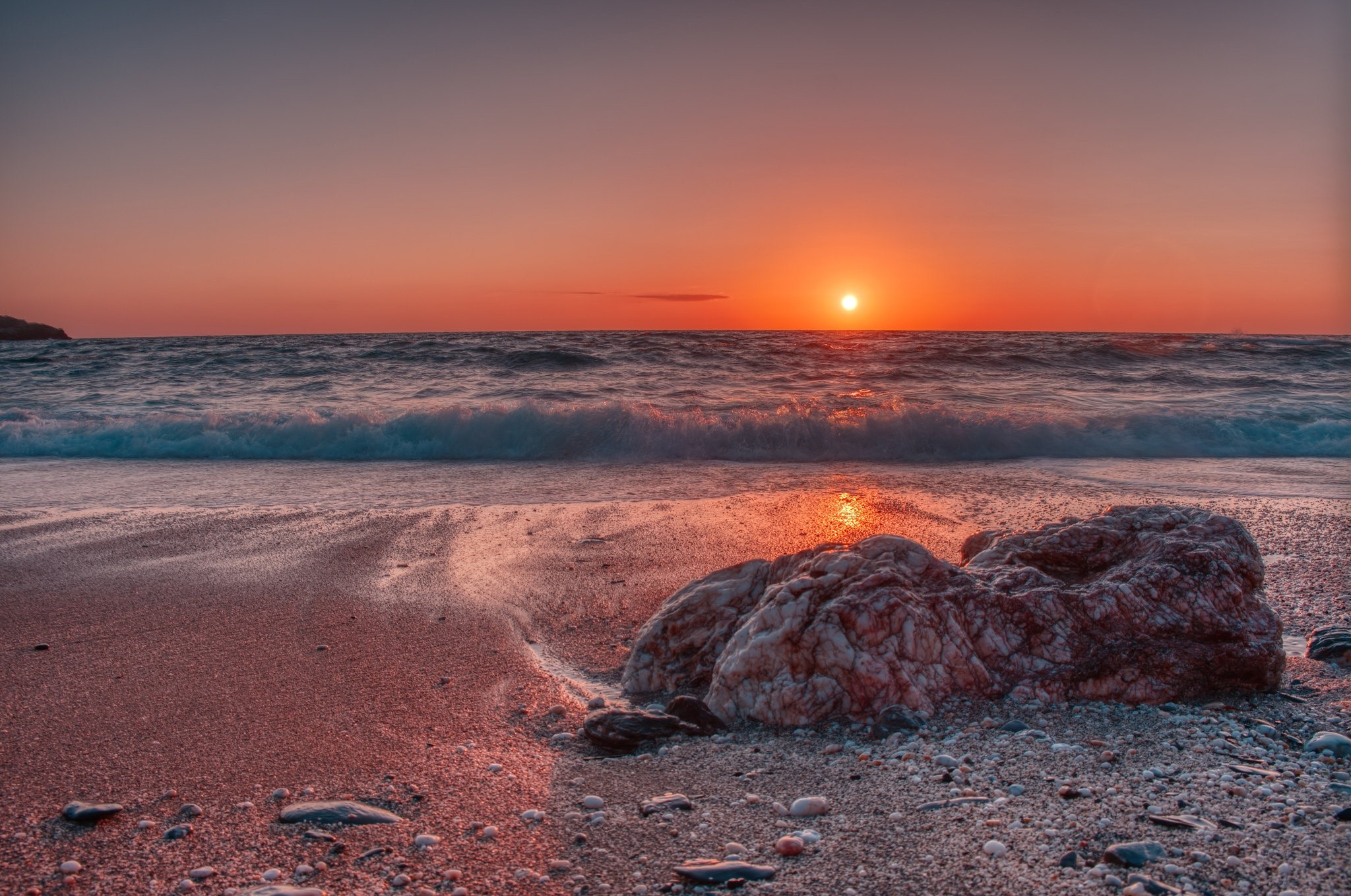 Sunset over the ocean with waves and rocks on the beach HD Wallpaper