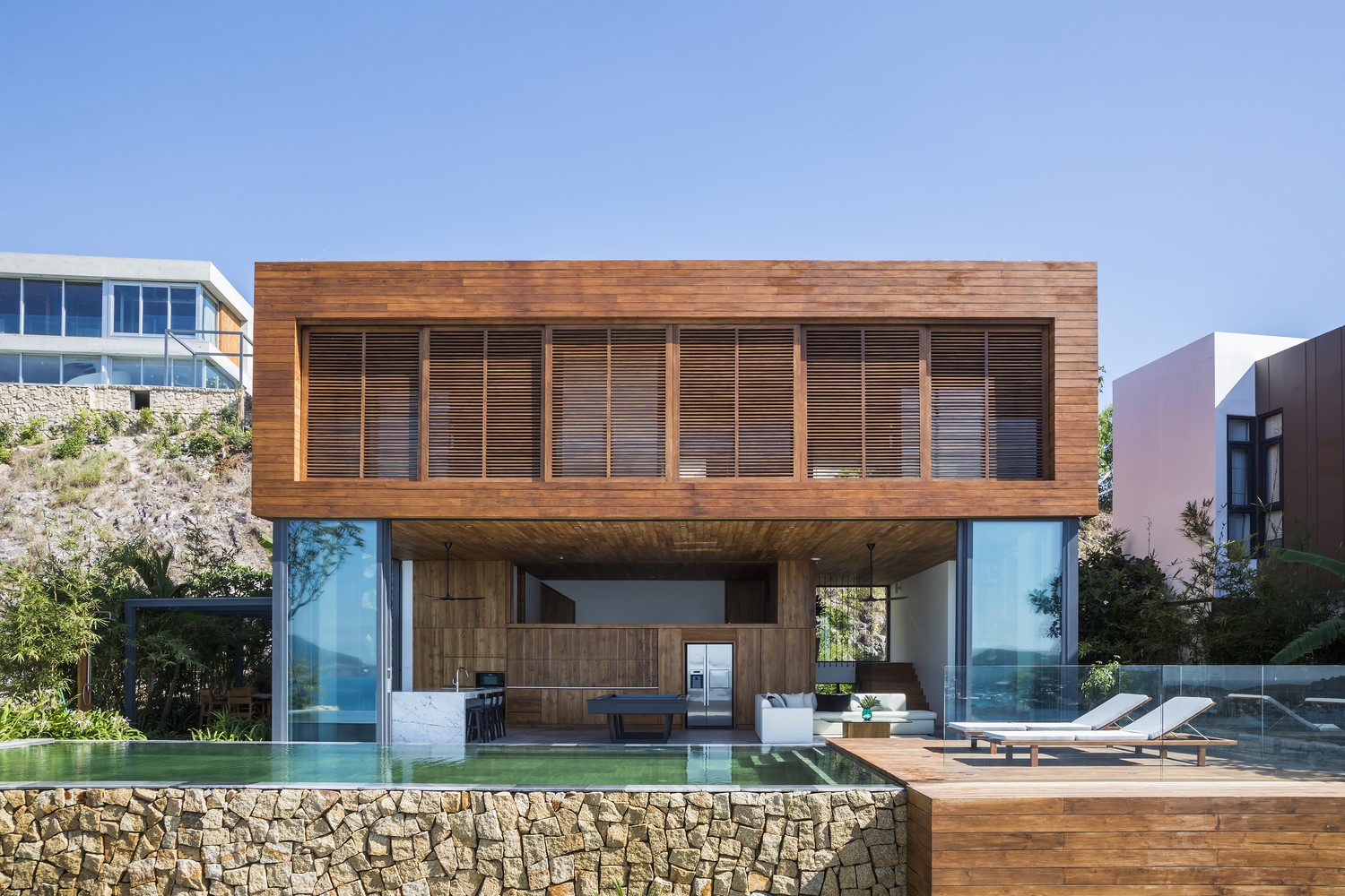 Modern wooden house with swimming pool and lounge chairs HD Wallpaper