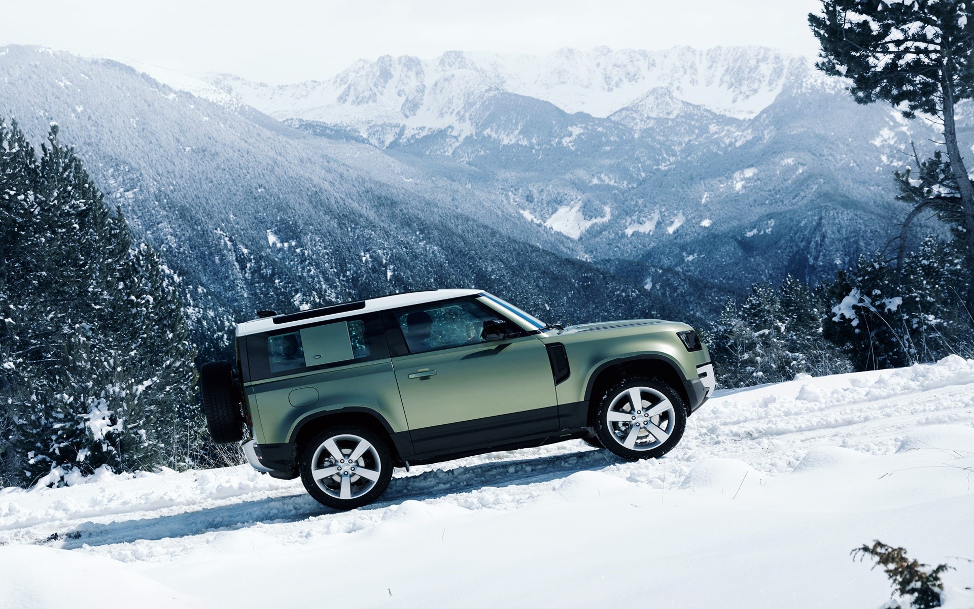 Land Rover Defender driving in snowy mountains HD Wallpaper