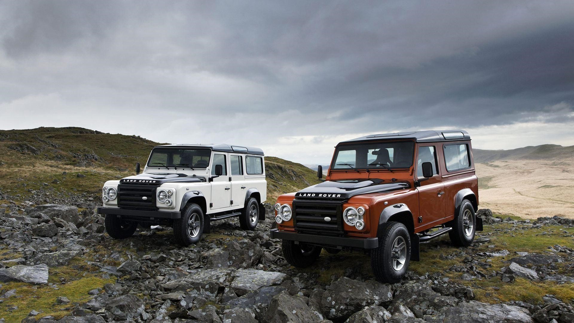 Two Land Rover Defender SUVs on rocky terrain HD Wallpaper
