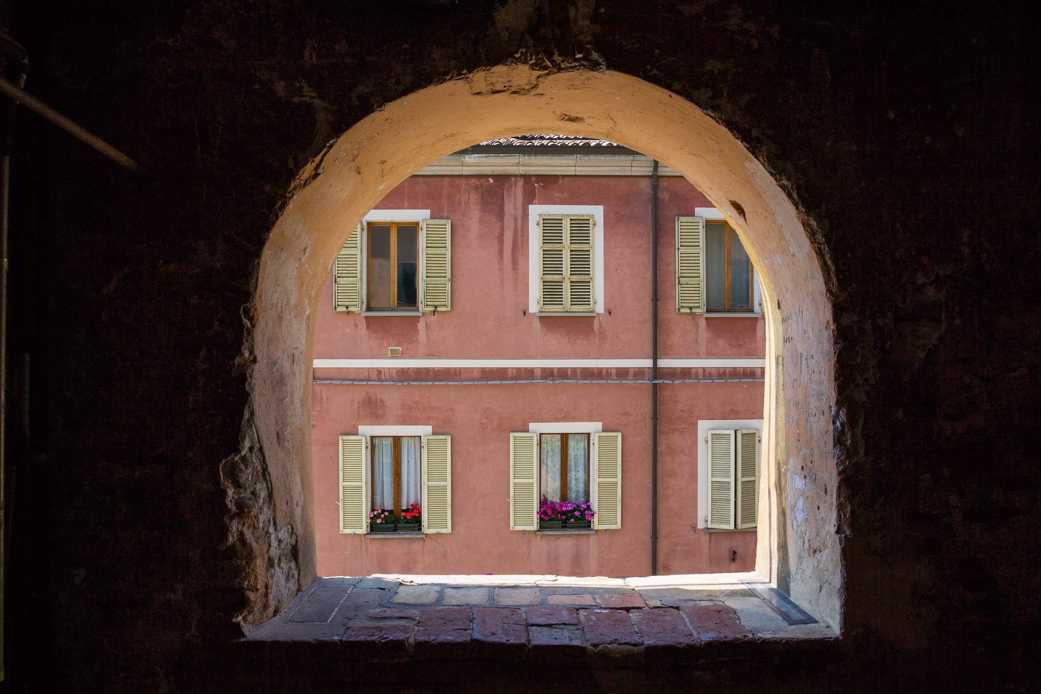 View through an archway of a pink building with windows HD Wallpaper