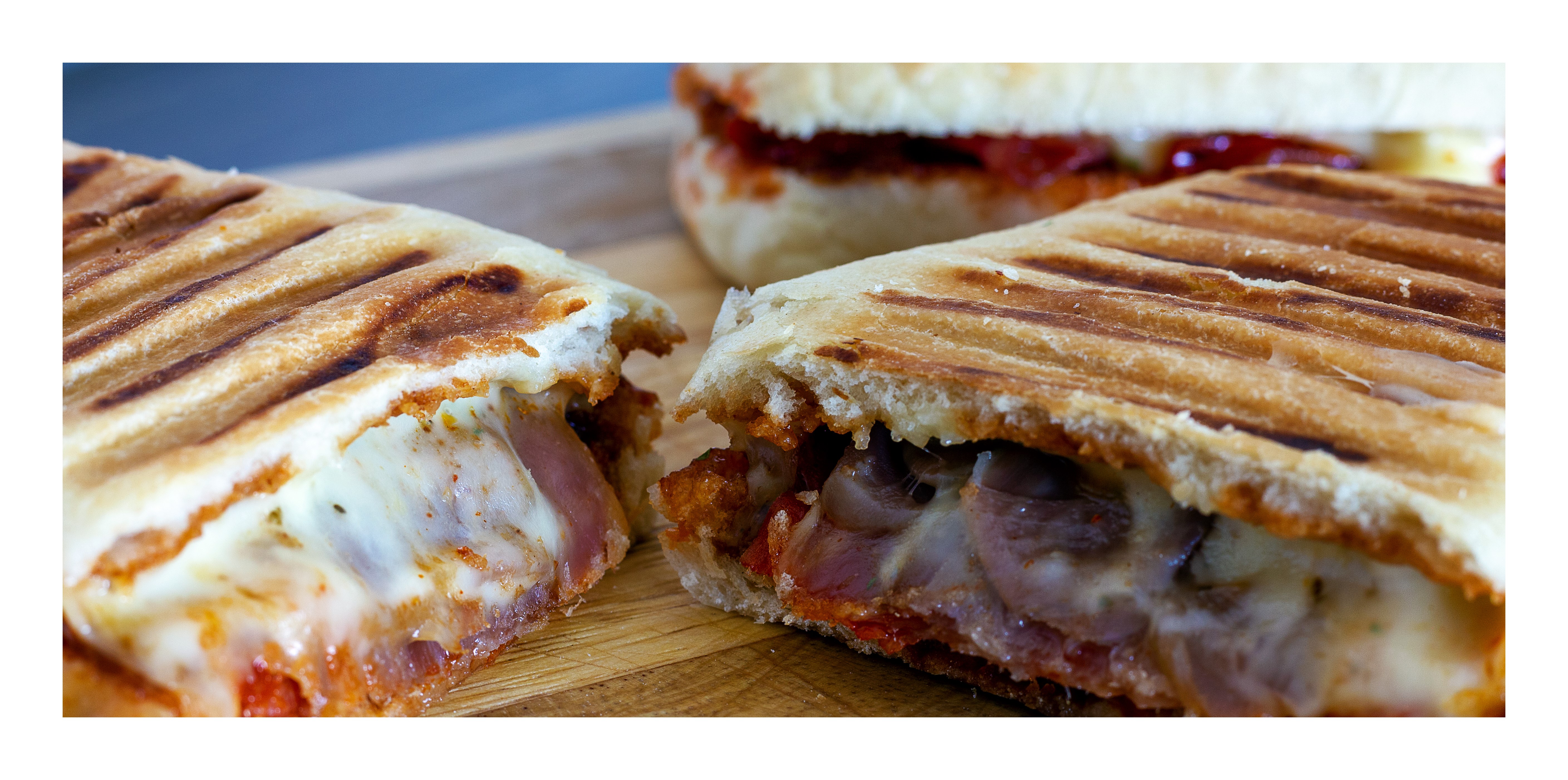 Panini sandwich with melted cheese and meat on a cutting board HD Wallpaper