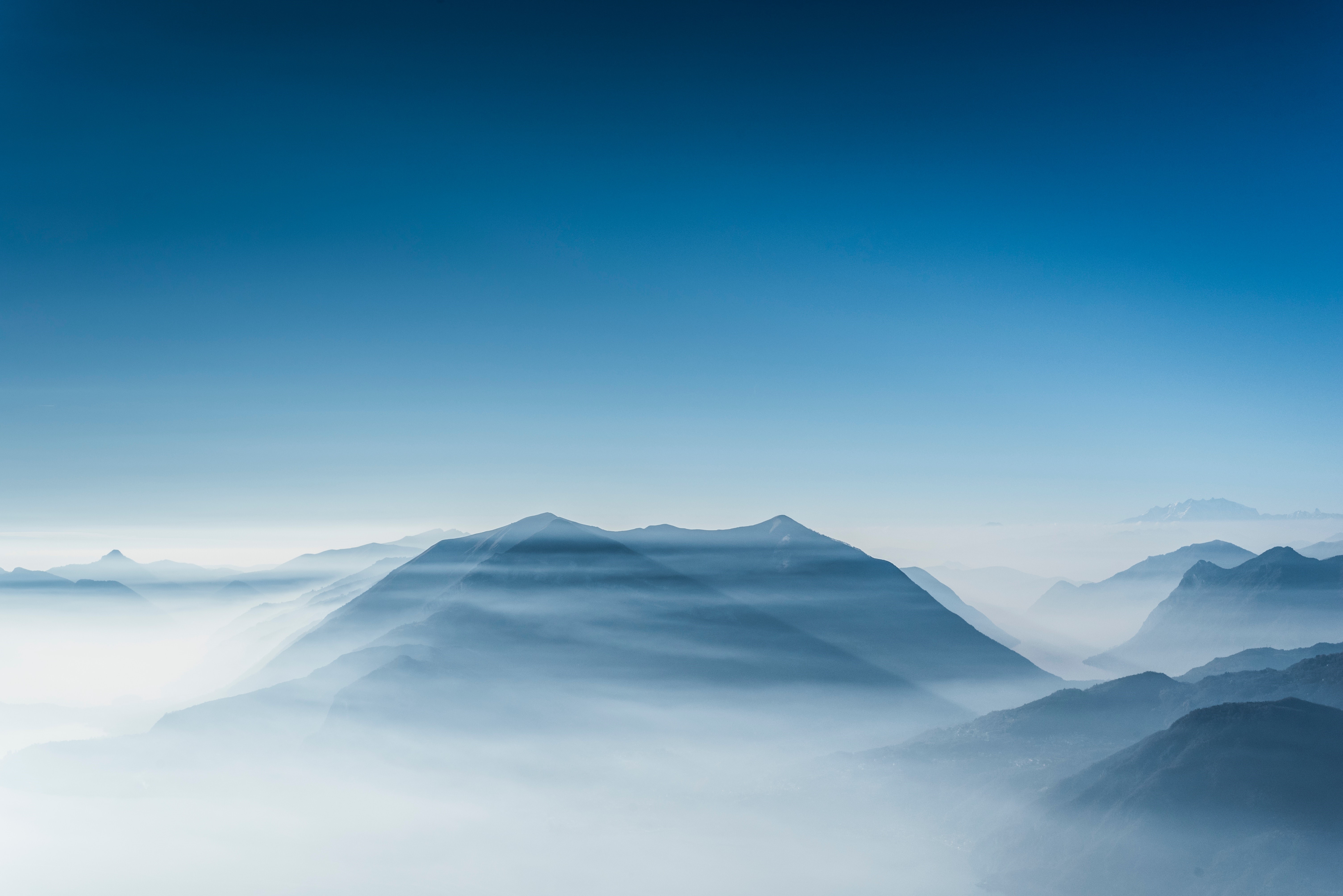 Mountains shrouded in mist under a clear blue sky HD Wallpaper