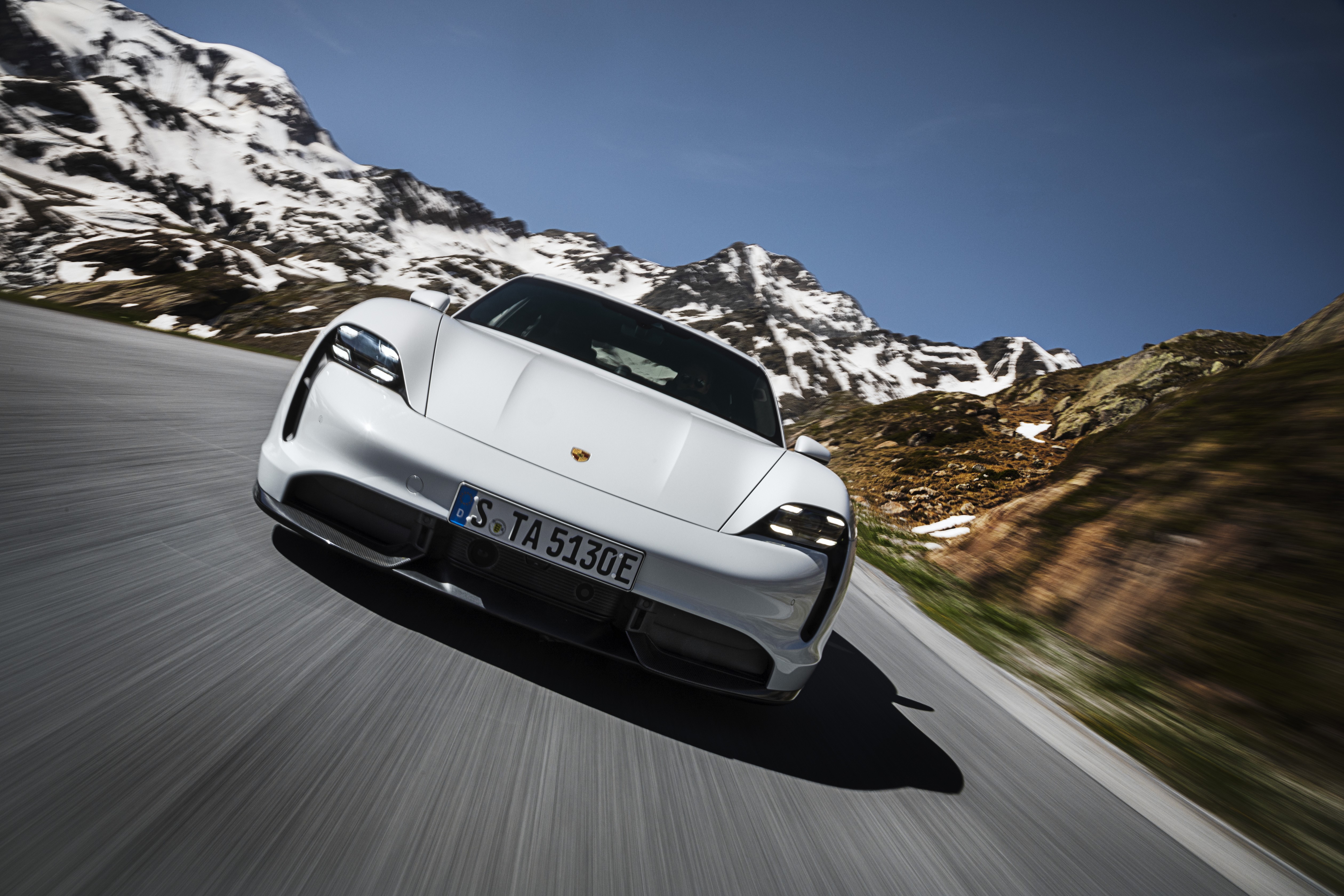 White Porsche Taycan driving on a mountain road HD Wallpaper
