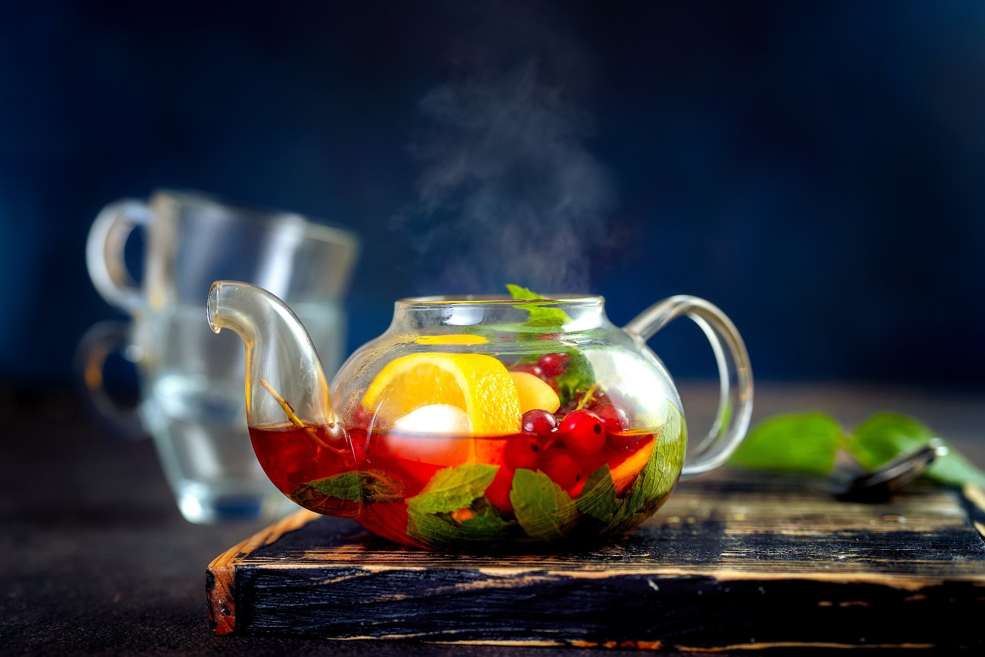 Steaming fruit tea in a glass teapot with lemon and berries HD Wallpaper