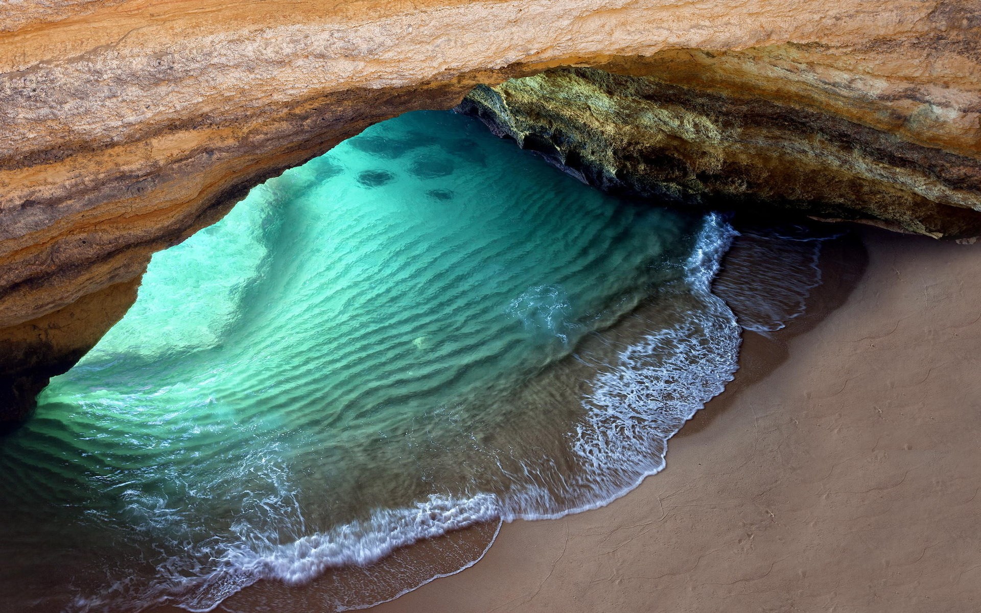 Cave opening with turquoise water and sandy beach HD Wallpaper