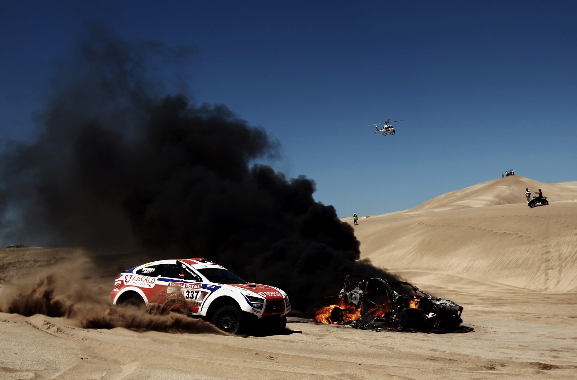 Race car and burning wreck in desert with helicopter HD Wallpaper