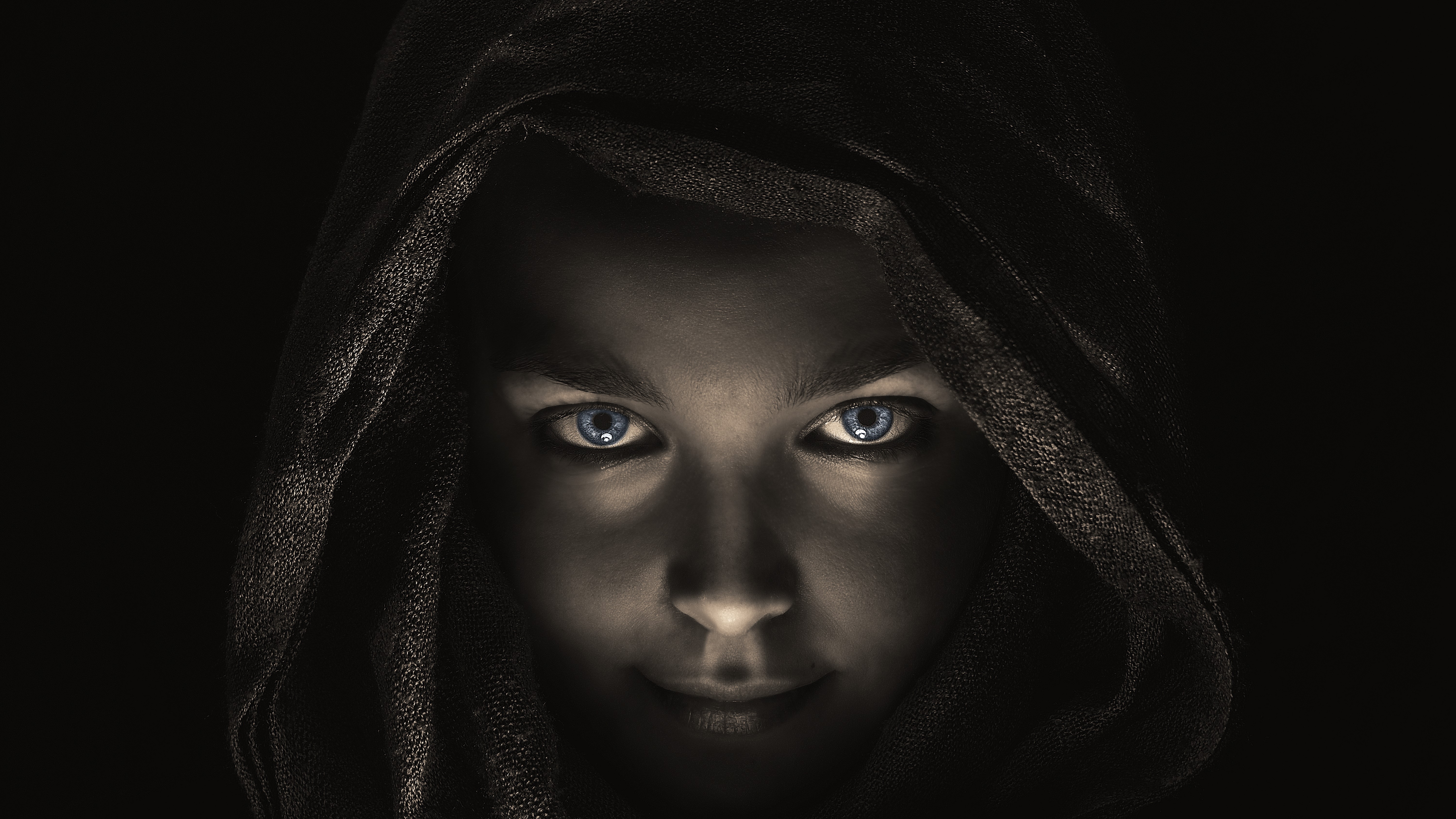 Woman with blue eyes wearing a dark hood HD Wallpaper
