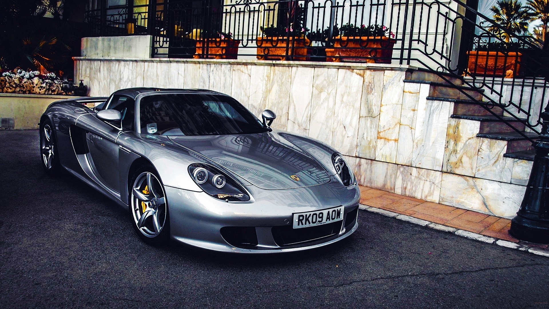 Silver Porsche Carrera GT parked in front of a building HD Wallpaper